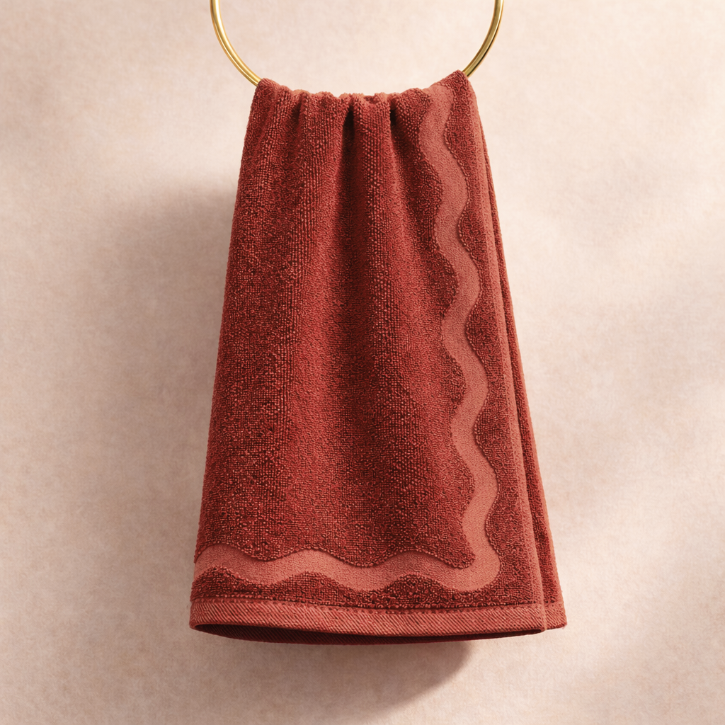 Red hand towel hanging on a gold ring against a beige background