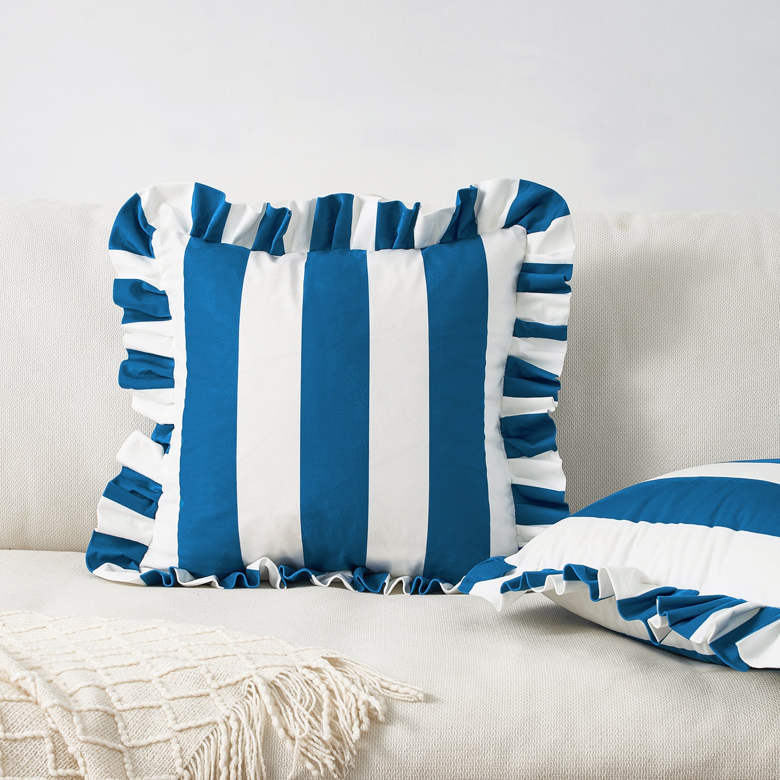 Blue and white striped pillows with ruffle edges on a light-colored sofa.