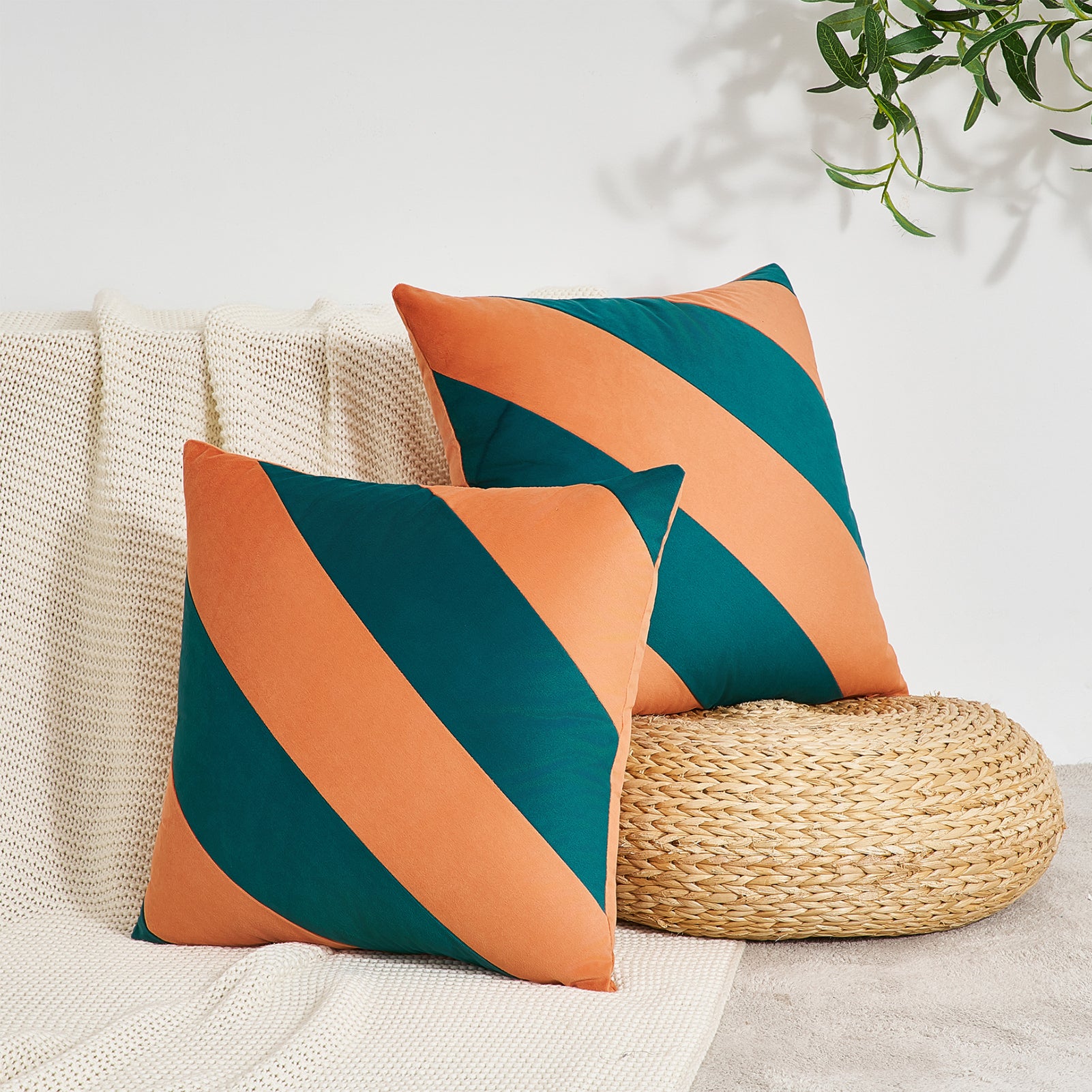 Two decorative pillows with orange and teal stripes on a beige surface.