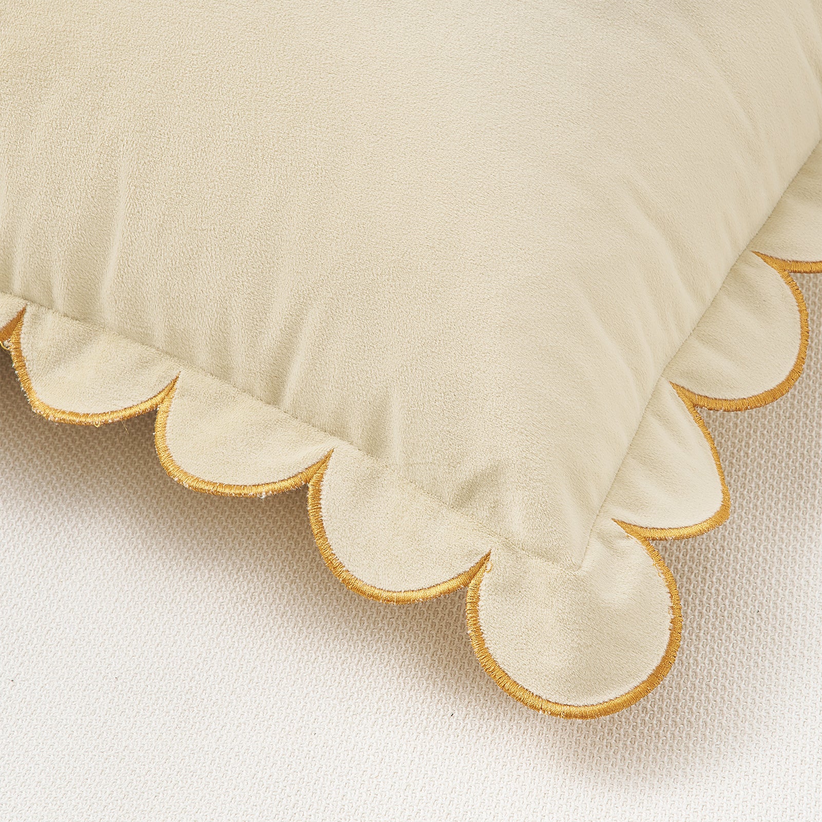 Beige pillow with scalloped edge on a matching fabric background