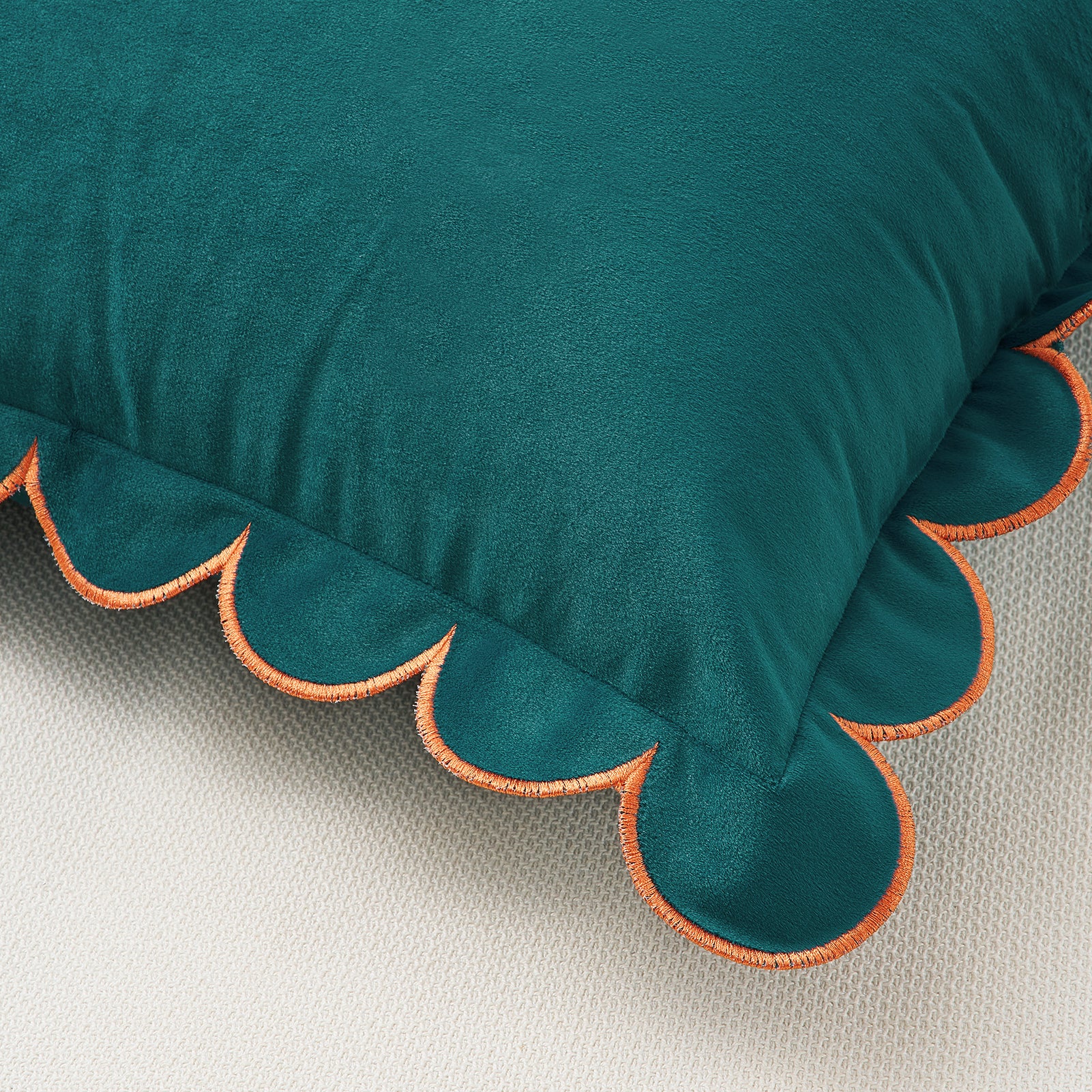 Teal pillow with scalloped edge on a beige background