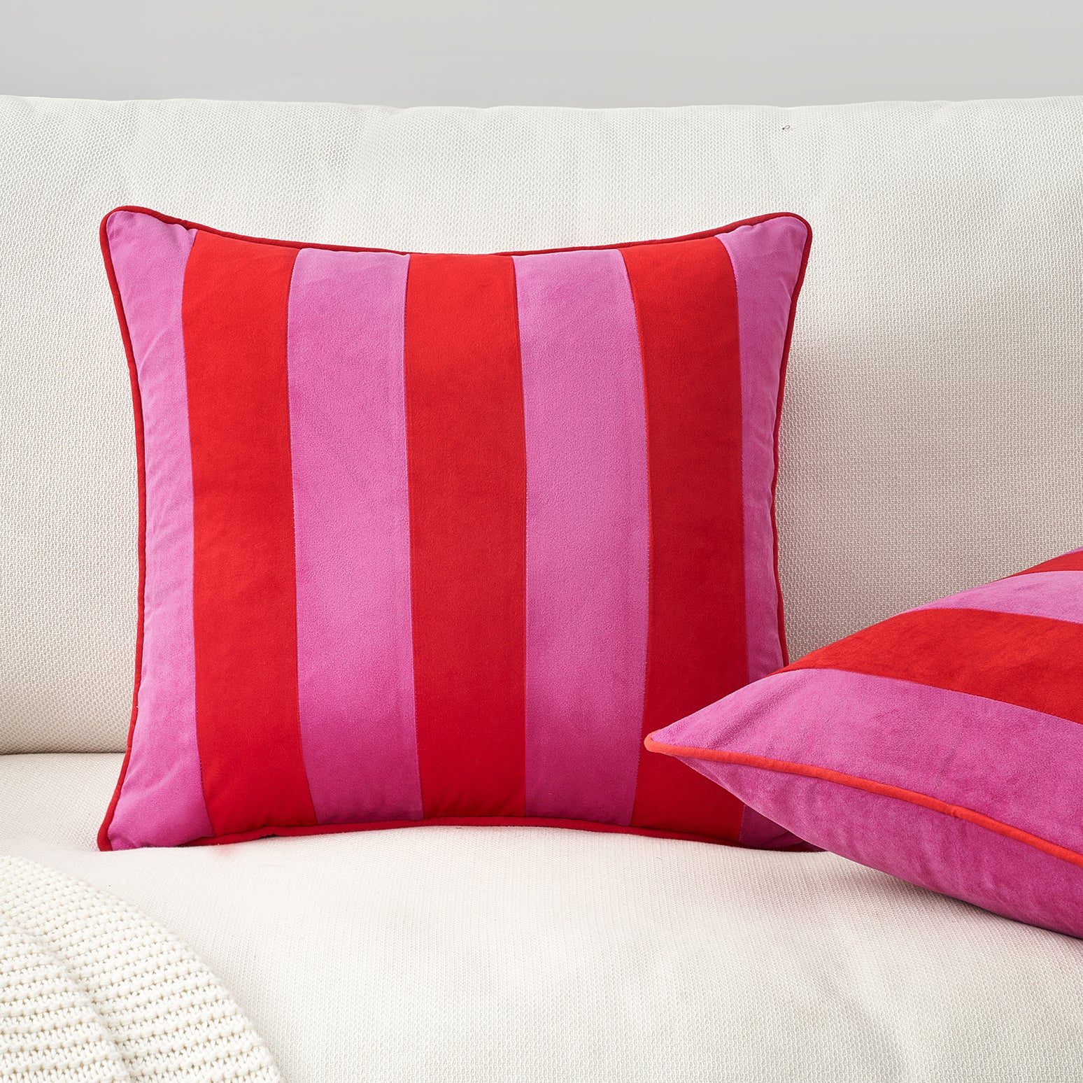 Red and pink striped pillows on a white sofa