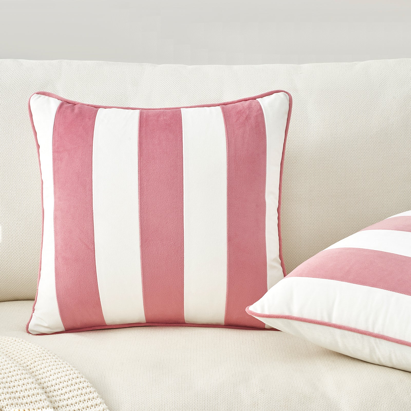 Pink and white striped pillows on a beige sofa