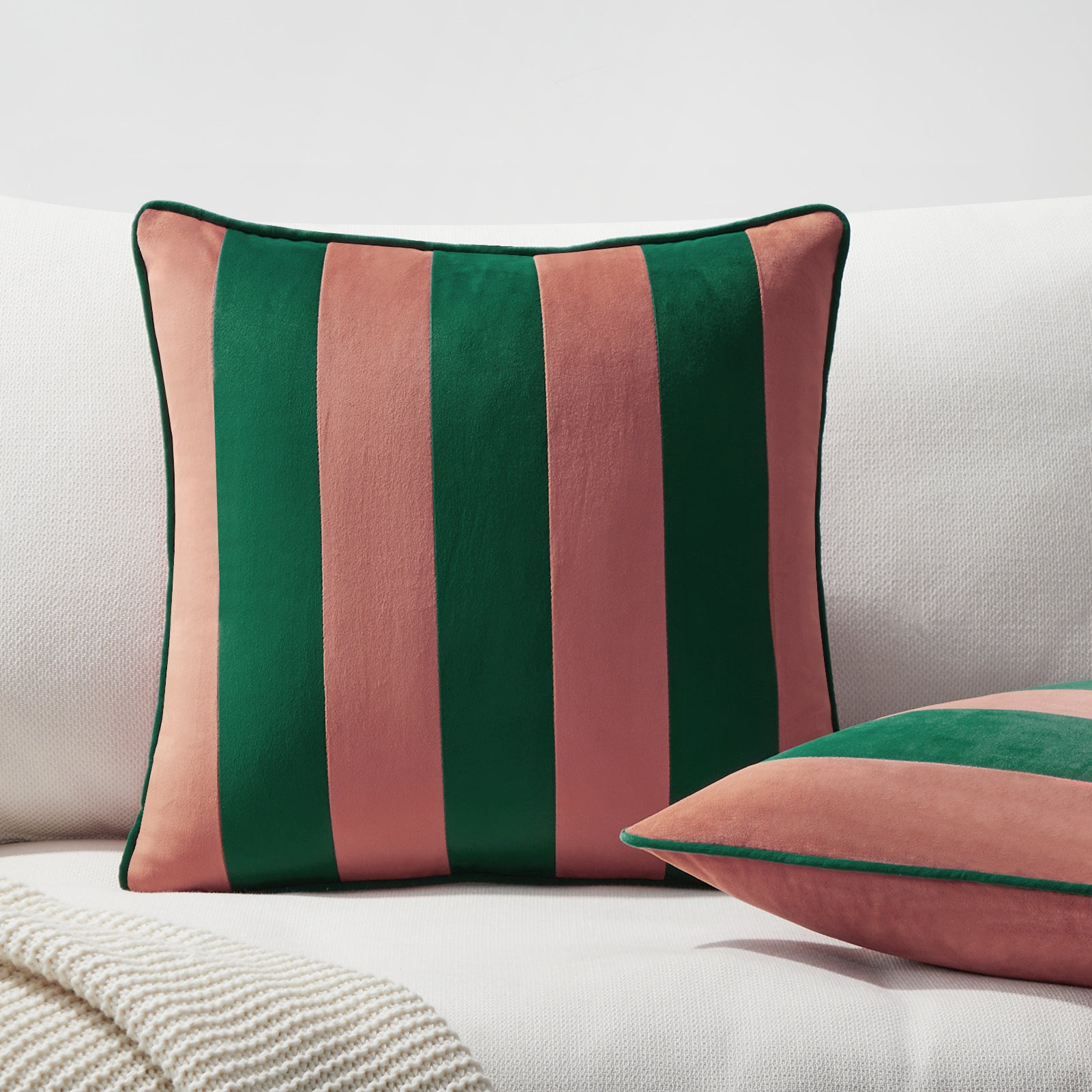 Striped green and pink pillow on a white sofa