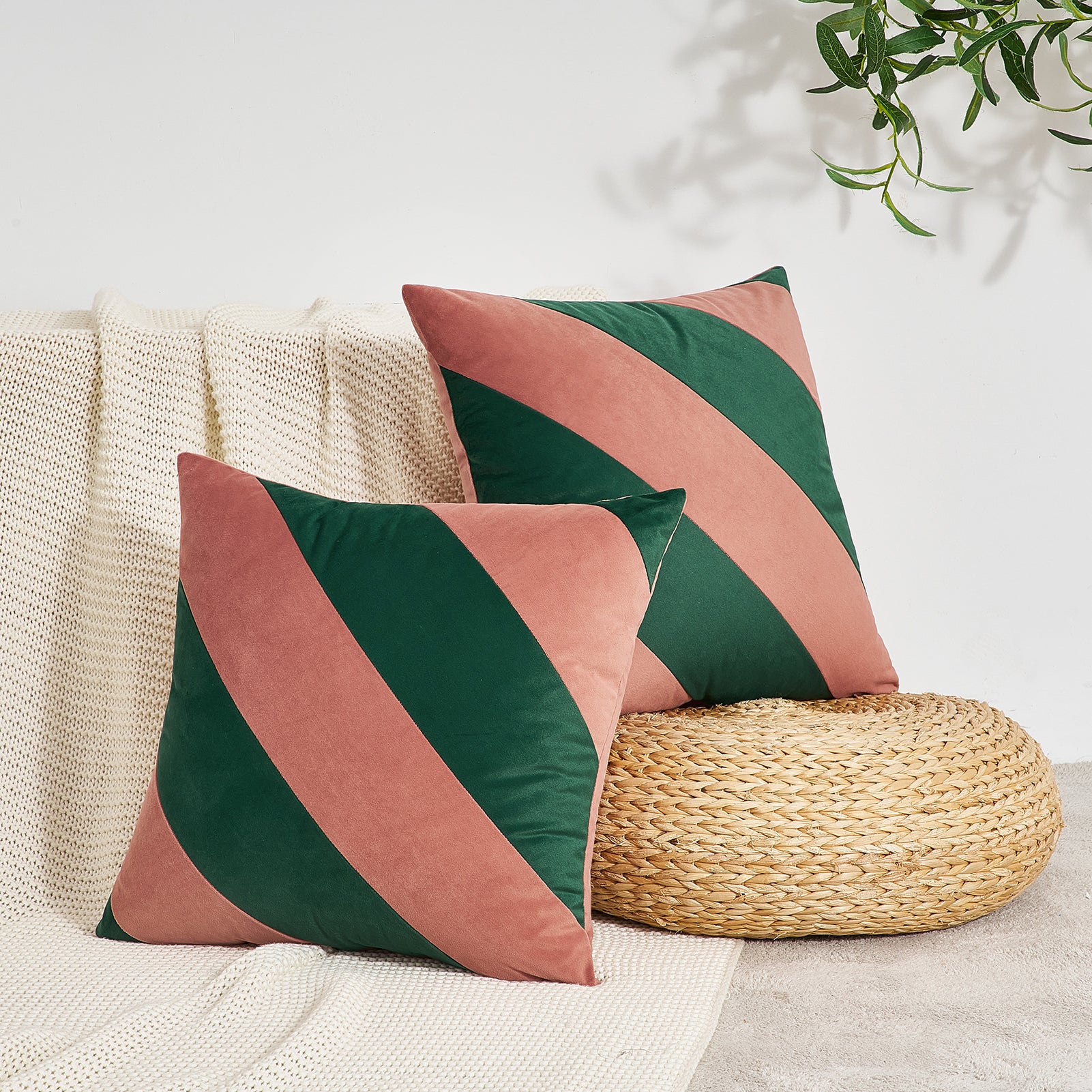 Two decorative pillows with green and pink stripes on a neutral background