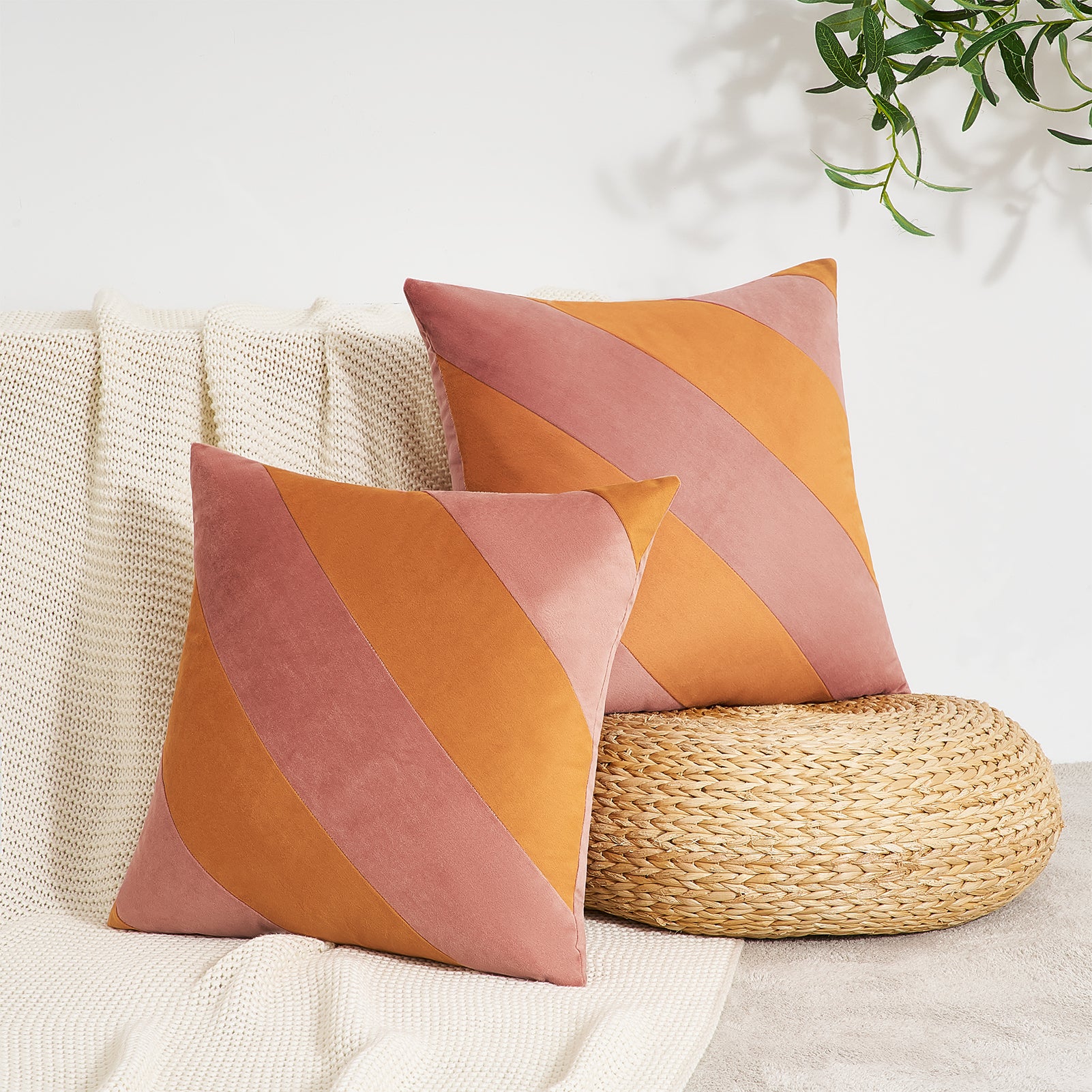 Two decorative pillows with orange and pink diagonal stripes on a beige couch.