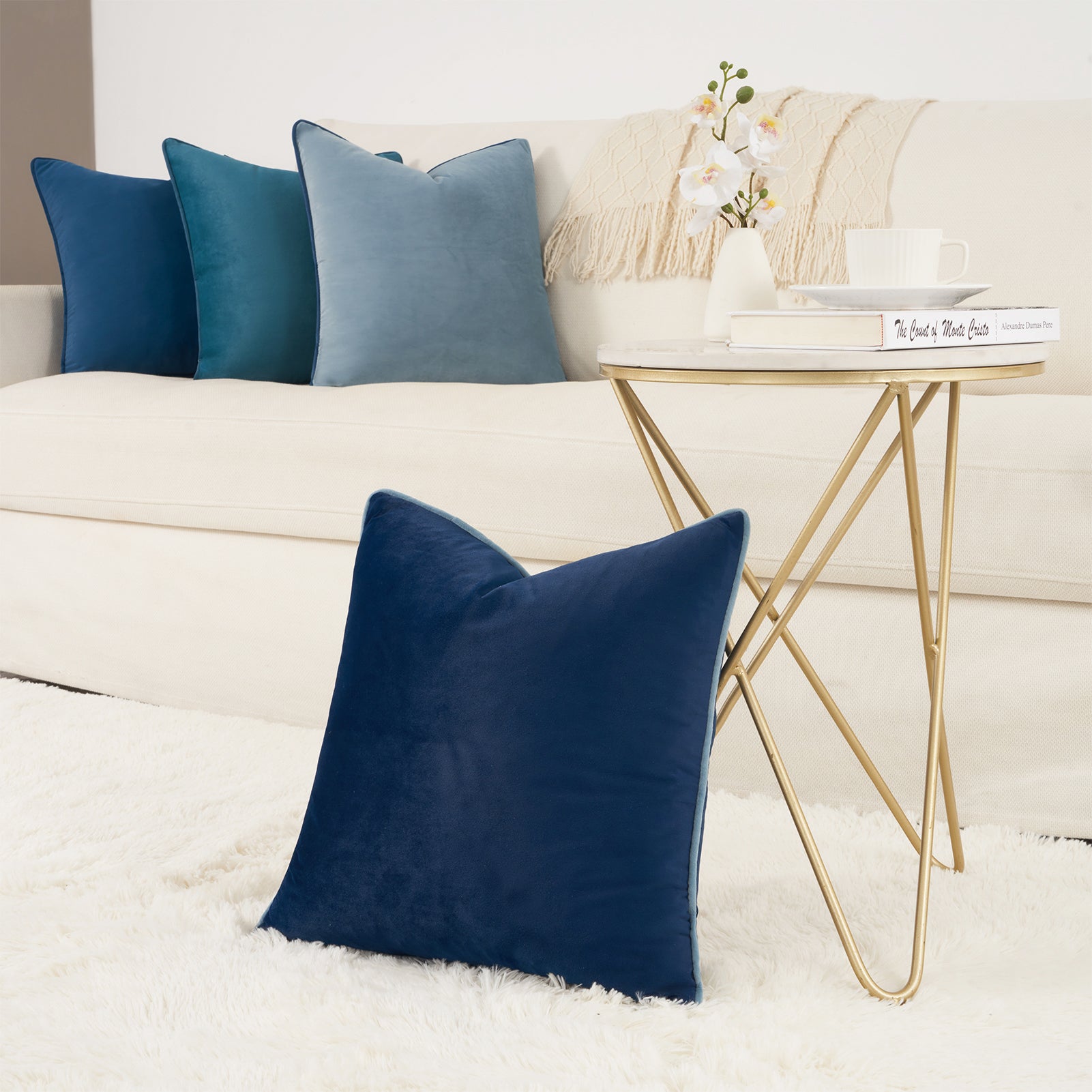 Navy blue pillows on a white sofa with a gold side table and decorative items.