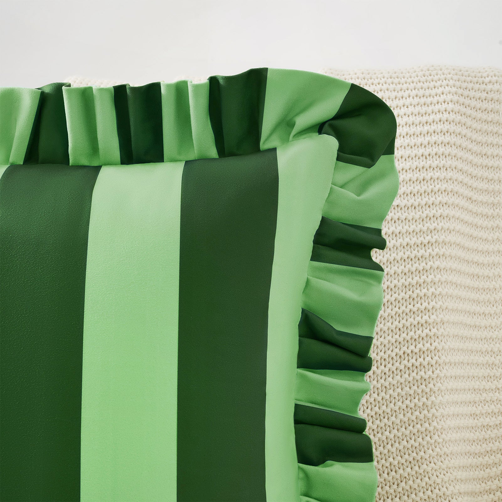 Green and gray striped fabric with ruffled edge on a neutral background