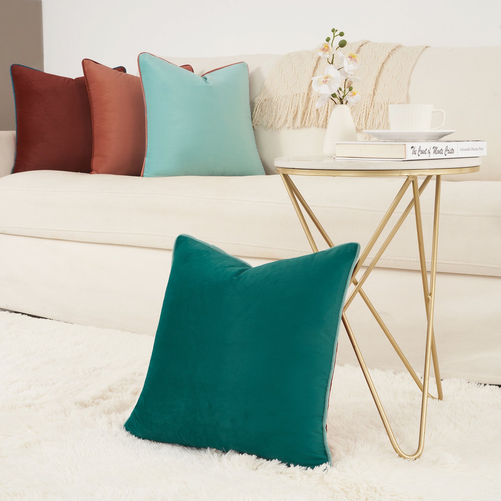 Teal pillow on a white sofa with a gold side table and decorative items.