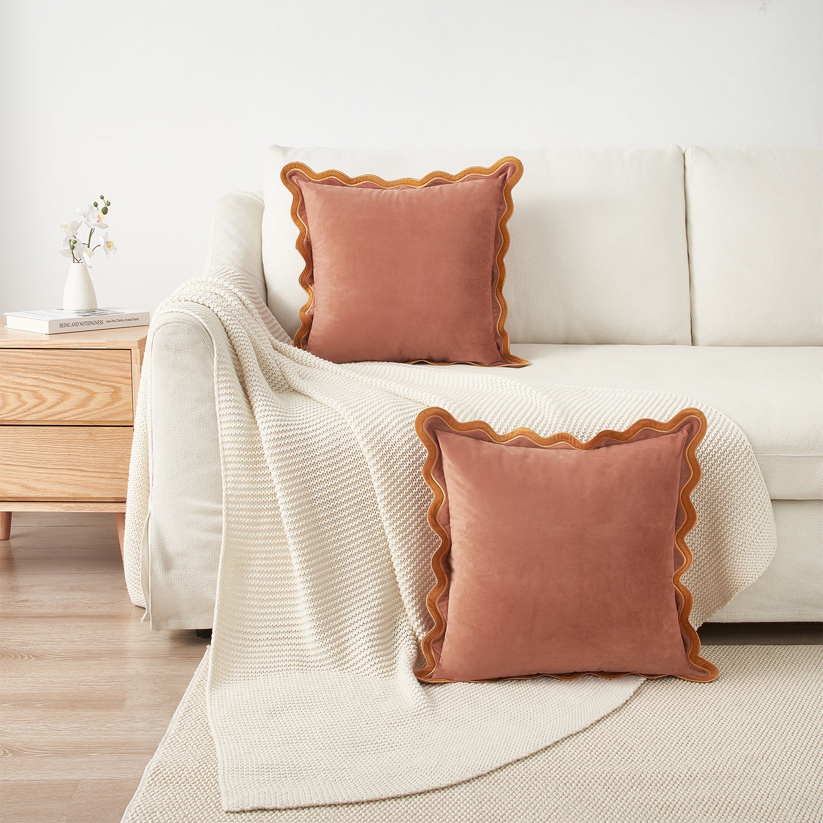 Pink pillows with scalloped edges on a white sofa in a living room setting.
