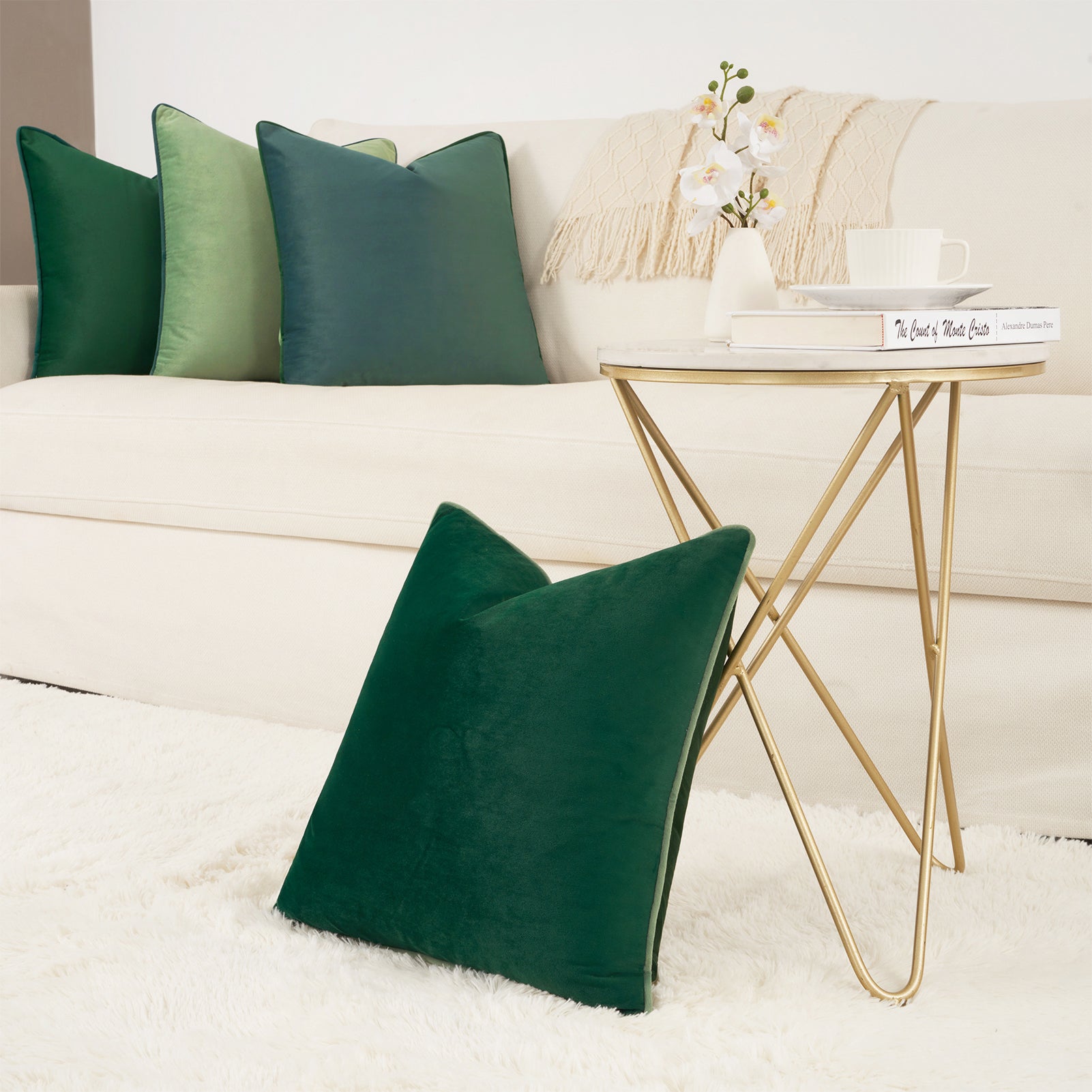 Green pillows on a beige sofa with a gold side table in a living room setting.