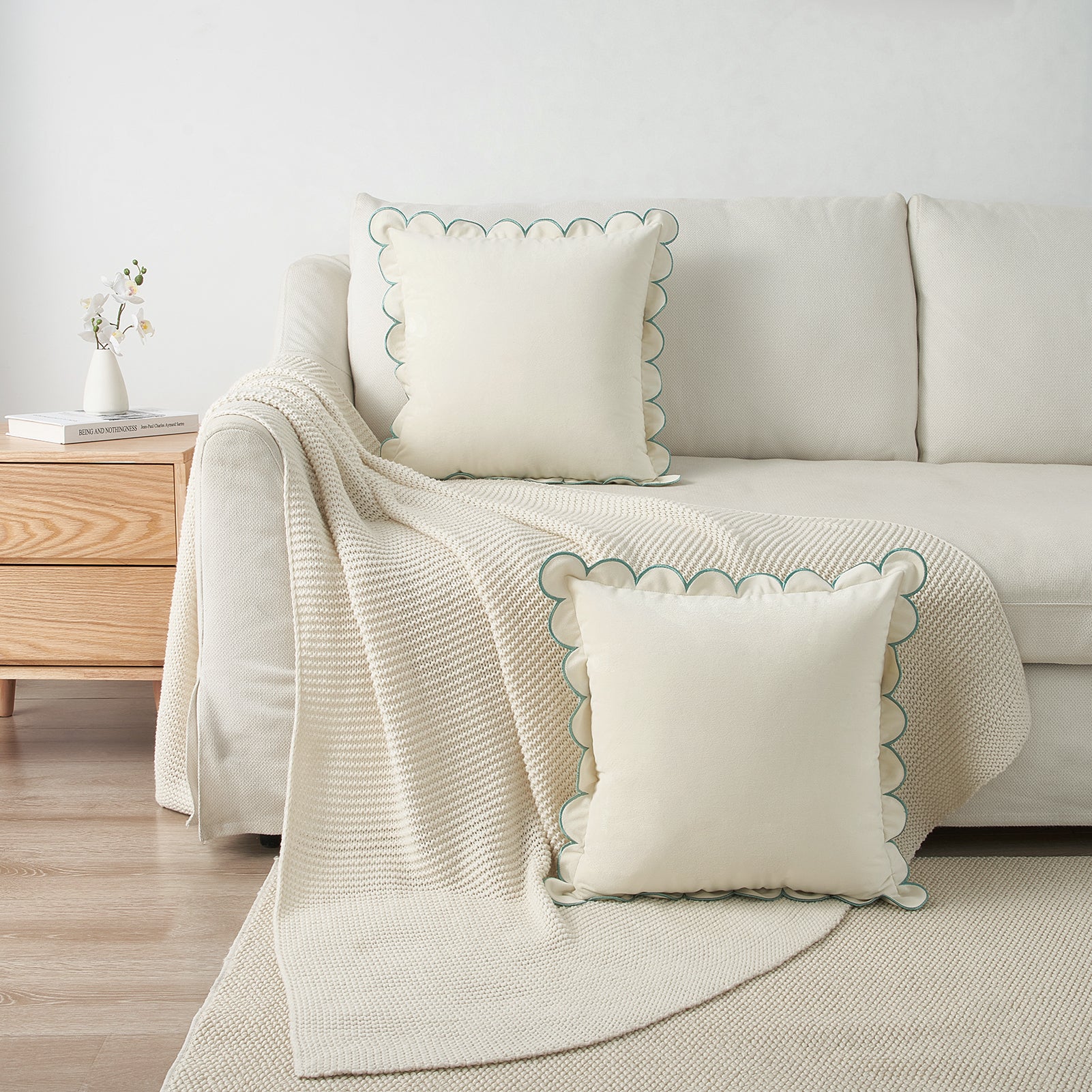 Beige sofa with decorative pillows and a matching throw blanket in a living room setting.
