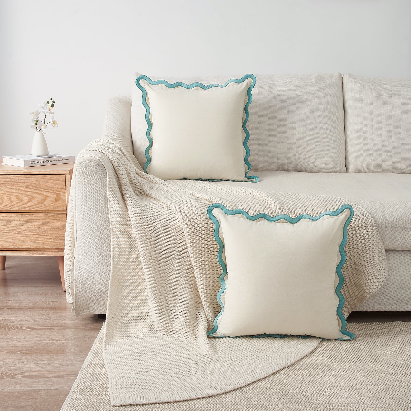 Beige sofa with decorative pillows and a throw blanket in a living room setting.