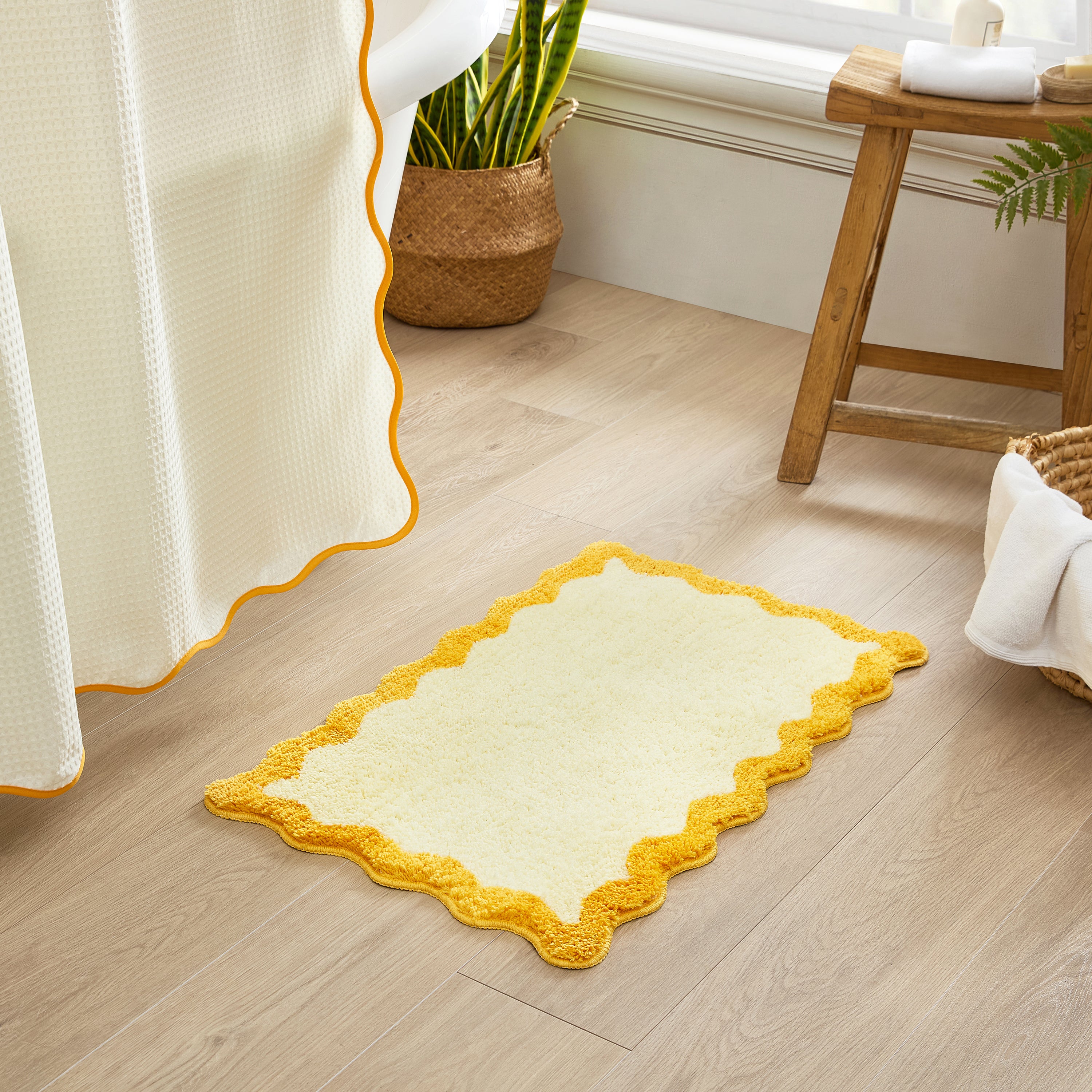 Yellow and white rug on a wooden floor with a plant and stool in the background