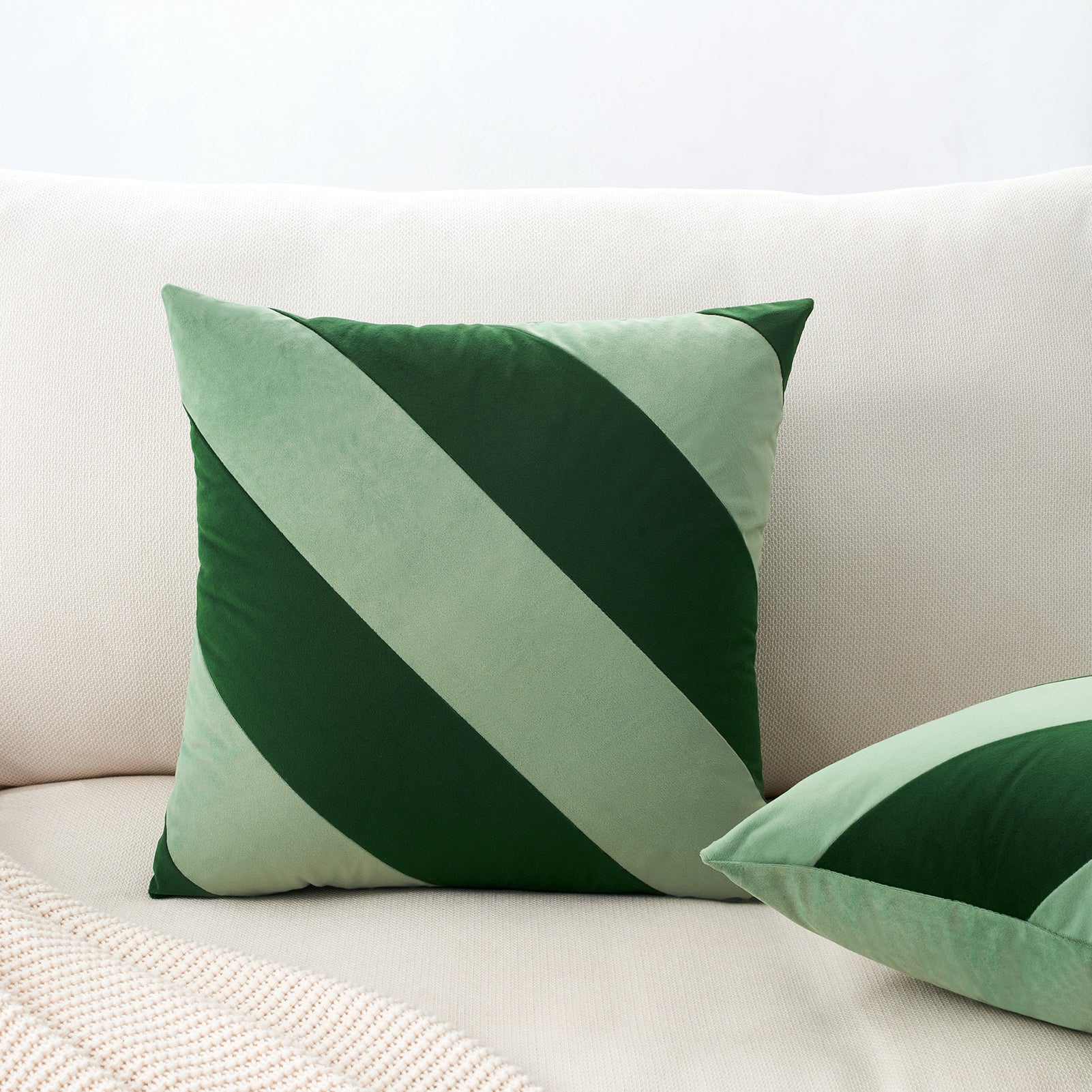 Green and white striped pillows on a beige sofa