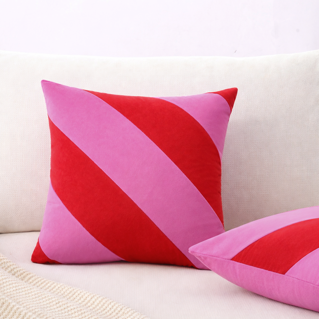 Two pink and red striped pillows on a beige couch.