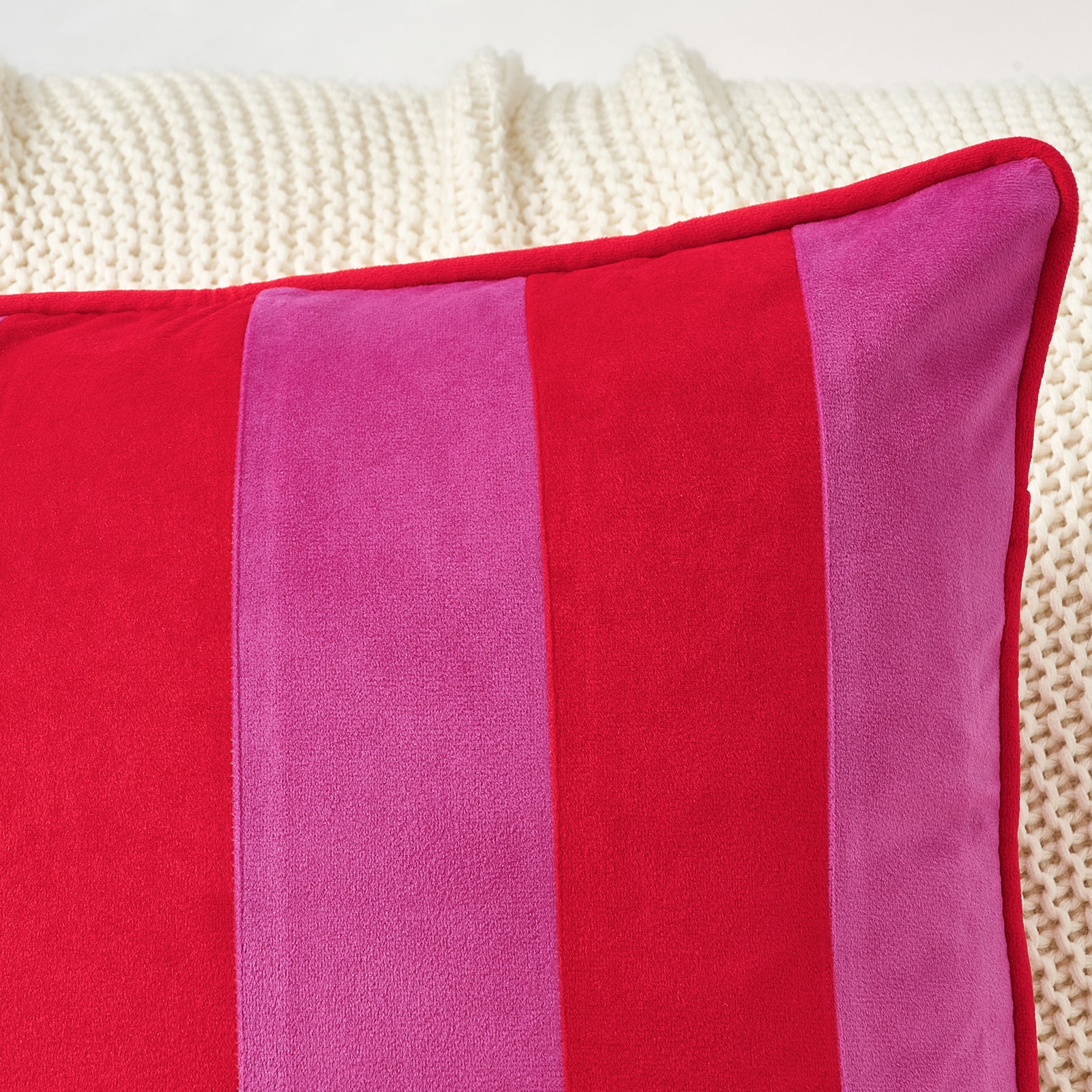 Close-up of a red and pink striped pillow on a textured surface