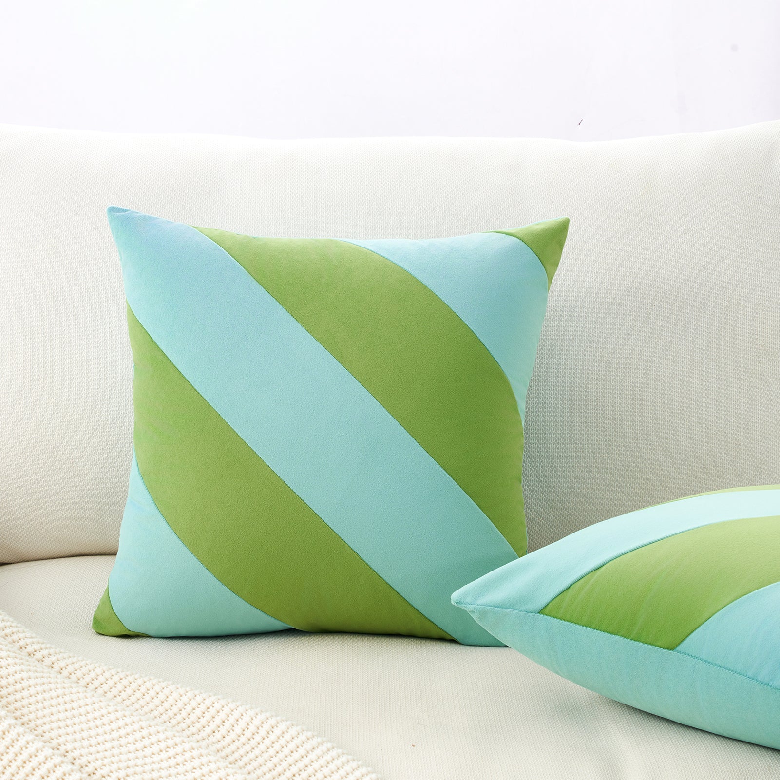 Green and blue striped pillows on a beige sofa