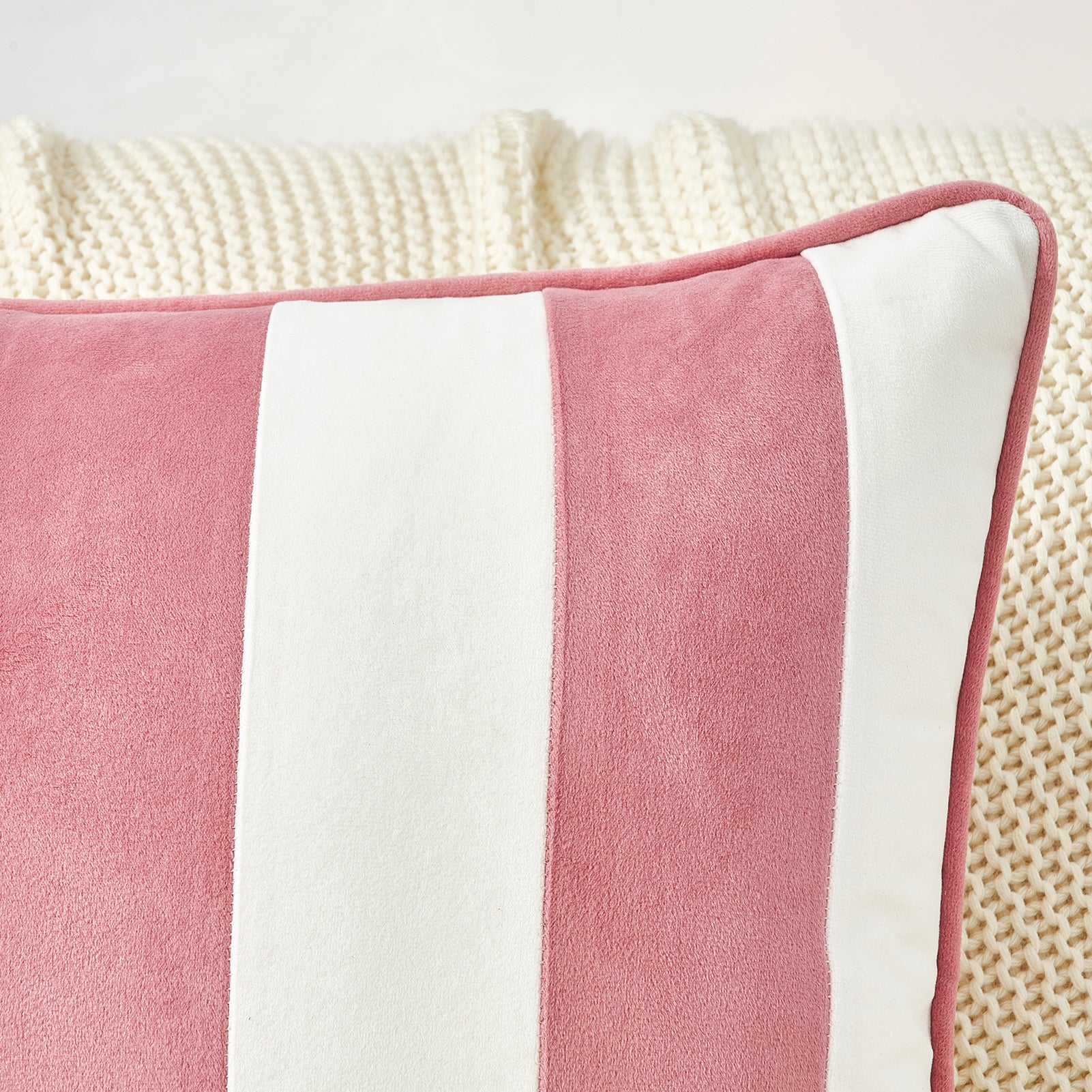 Close-up of a pink and white striped pillow on a textured surface.
