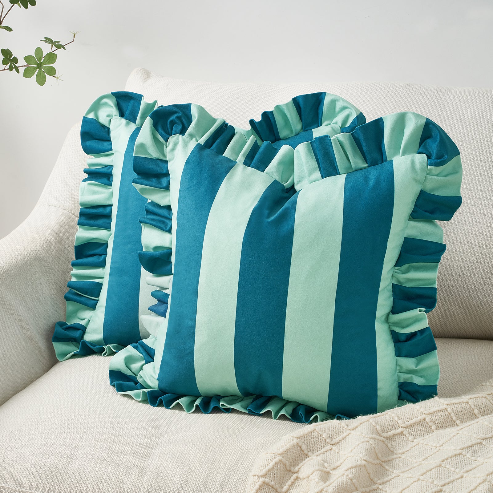 Teal and light blue striped pillow with ruffled edges on a beige couch.
