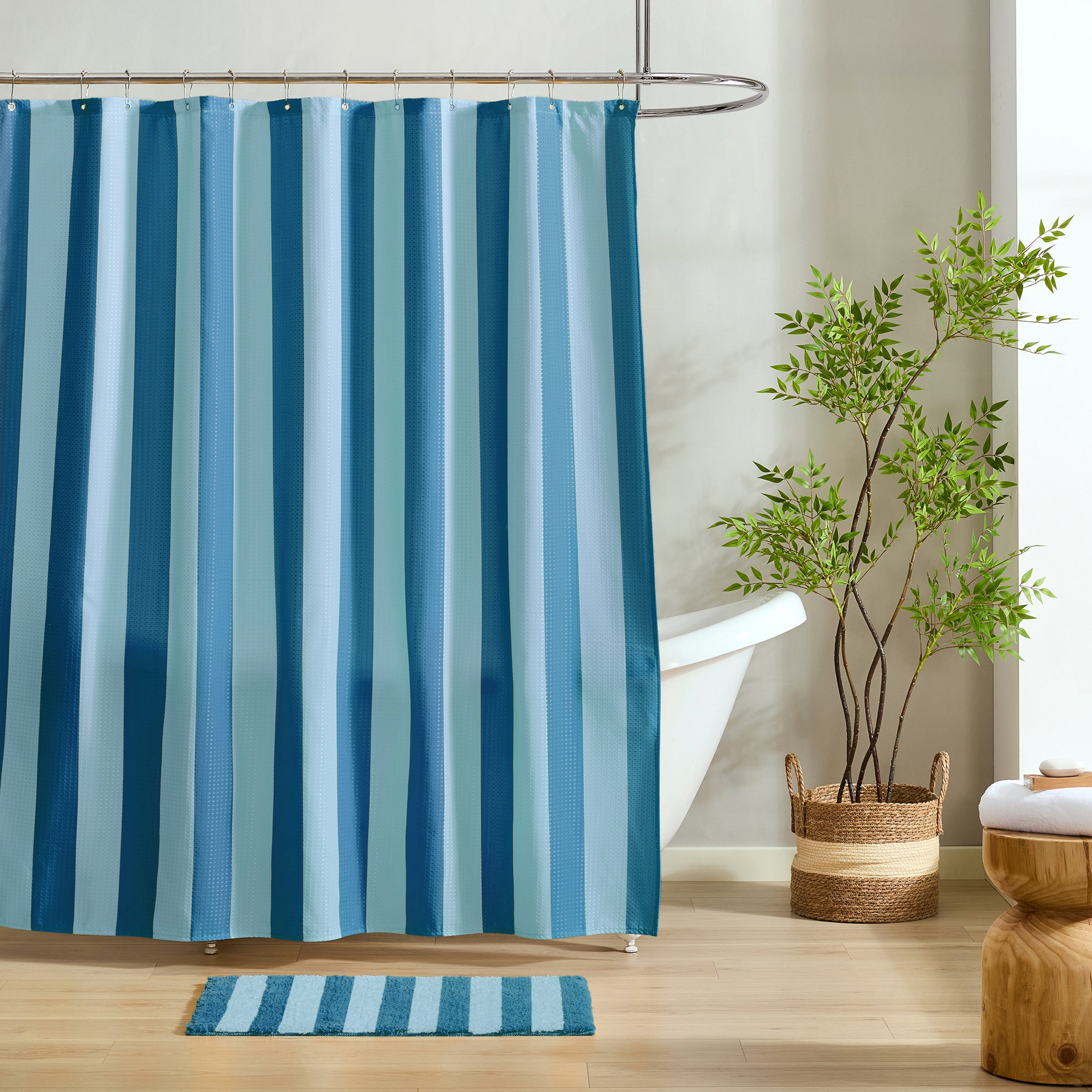 Blue striped shower curtain in a bathroom with a plant and rug.