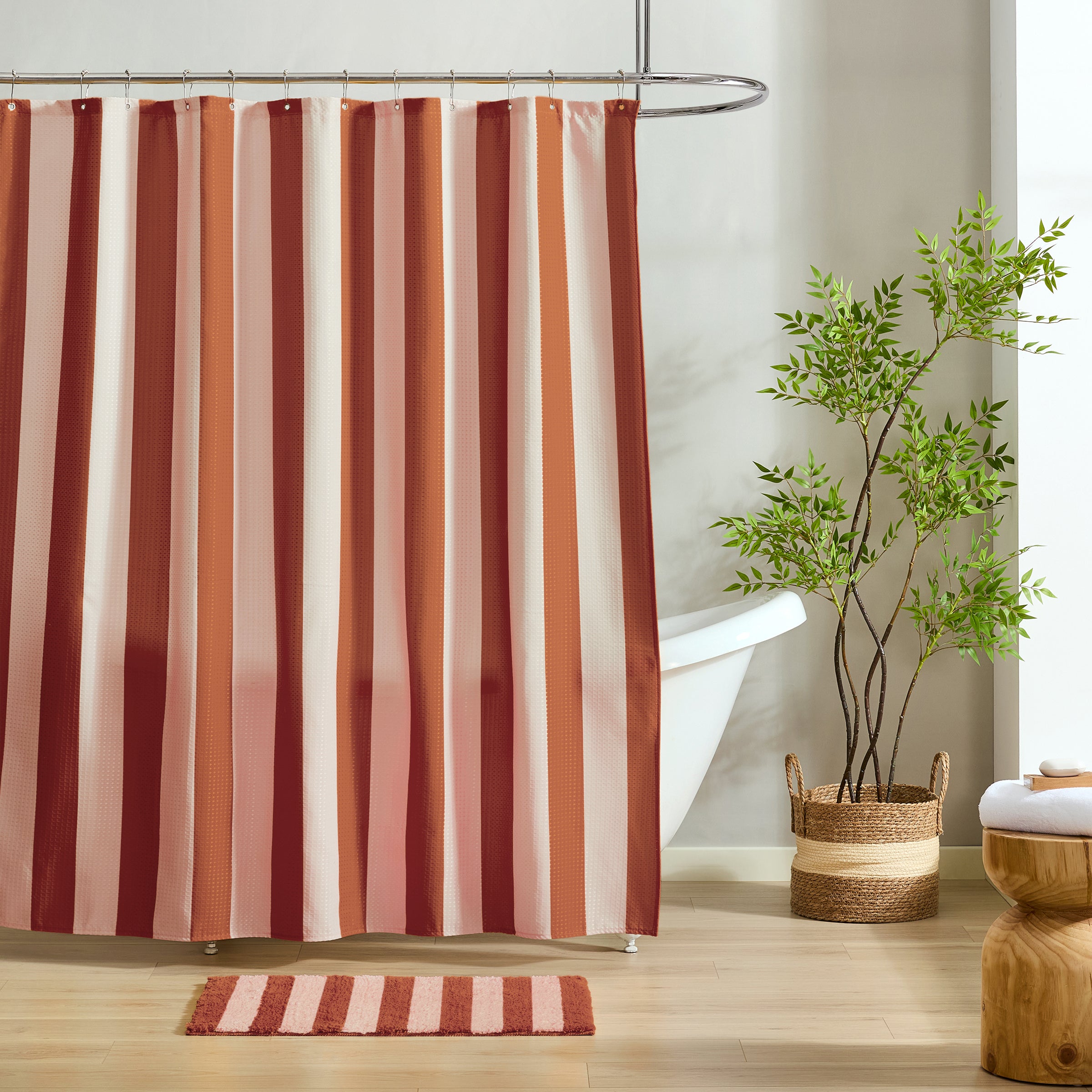Striped shower curtain with a plant and rug in a bathroom setting