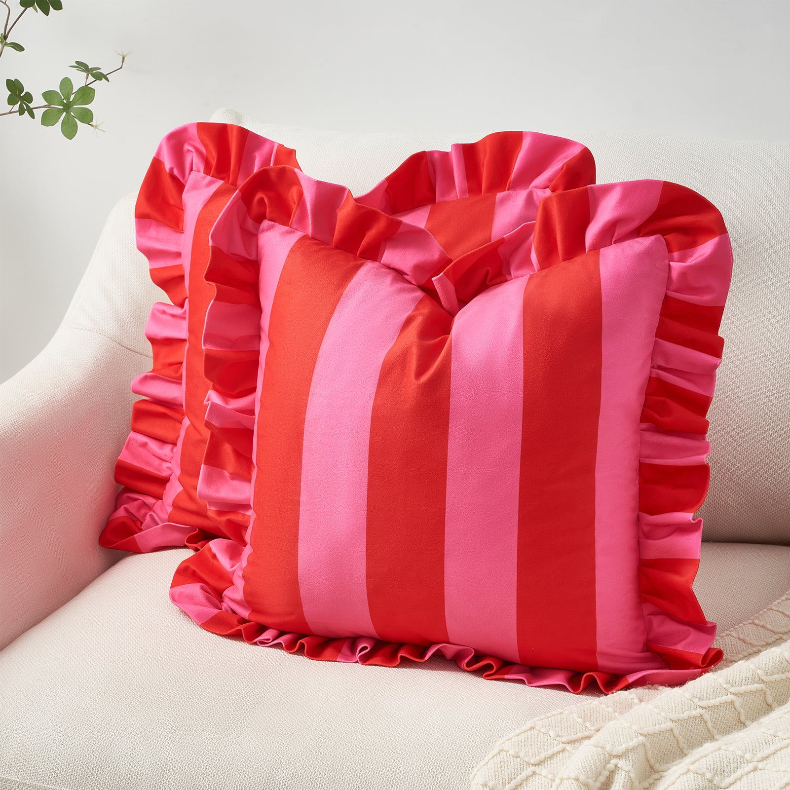 Pink and red striped pillow with ruffled edges on a light-colored sofa.