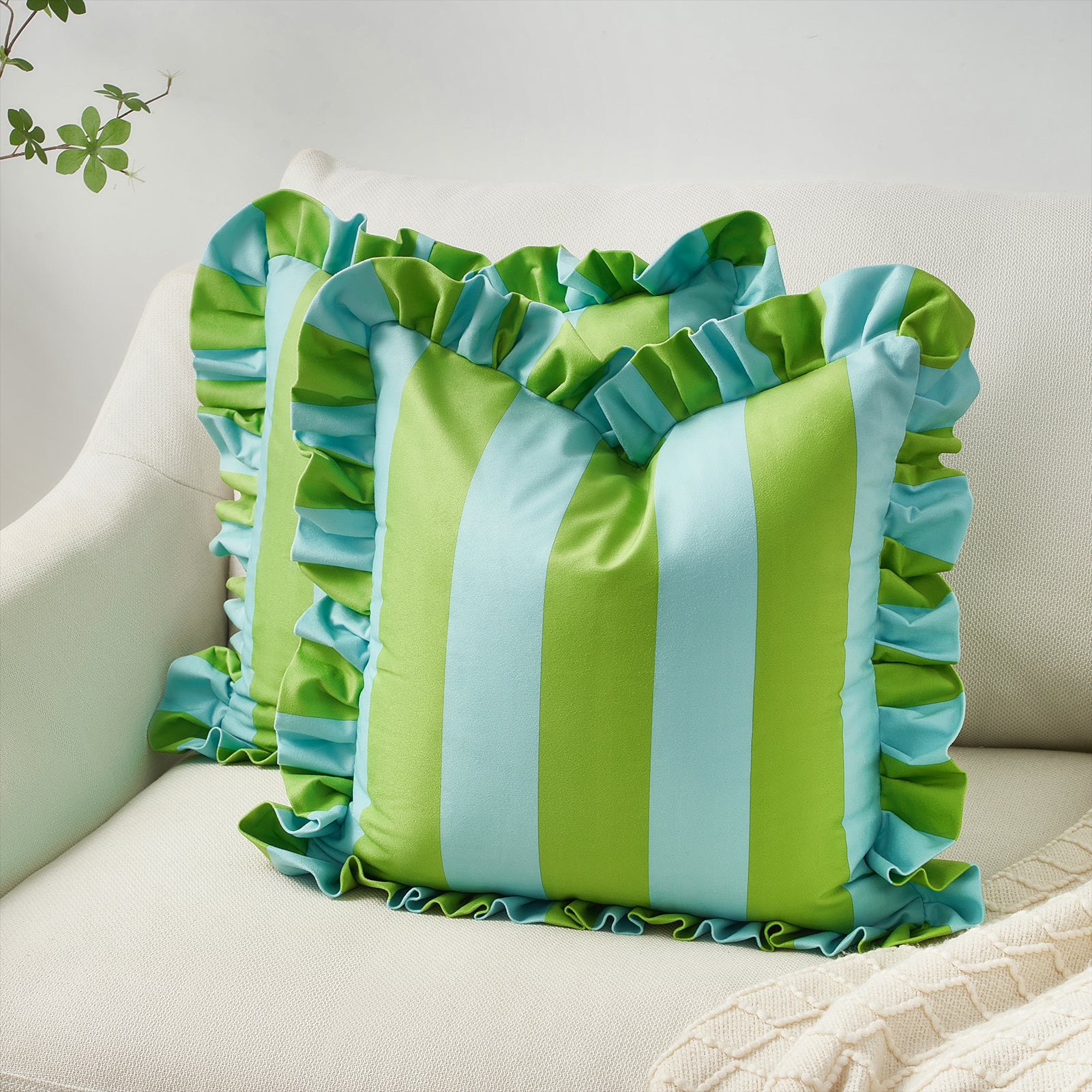 Green and blue striped pillow with ruffled edges on a beige couch.