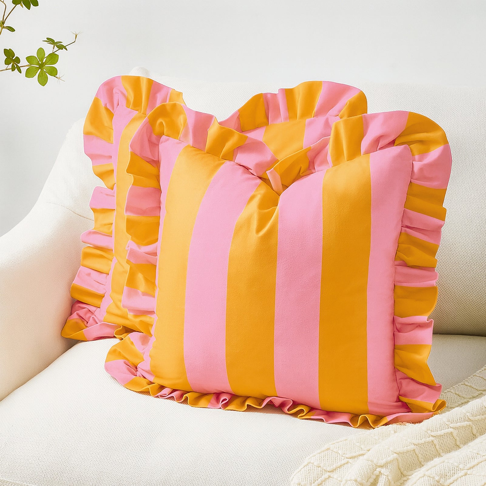 Pink and yellow striped pillow with ruffled edges on a white couch.
