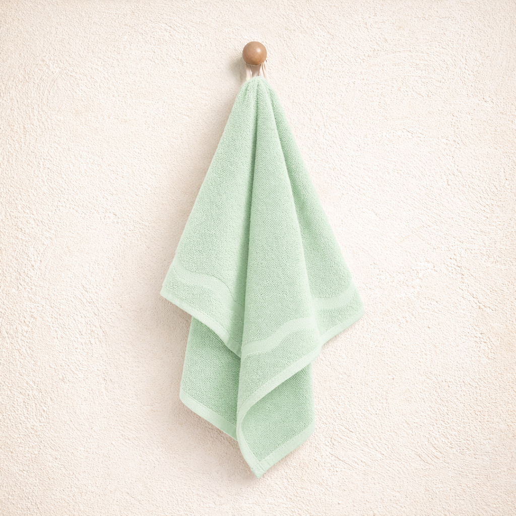 Green towel hanging on a wooden hook against a white wall