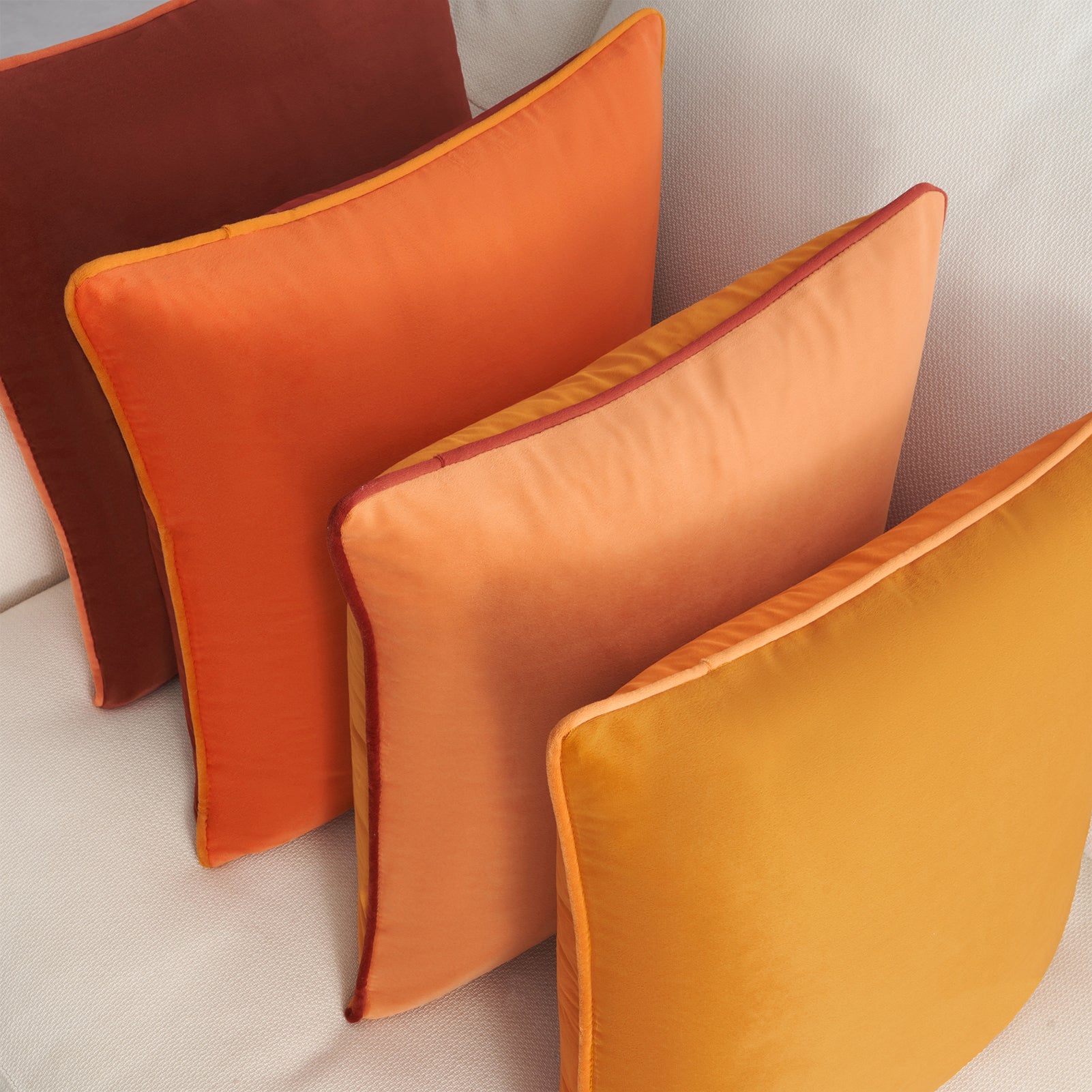 Orange and red cushions on a light gray sofa