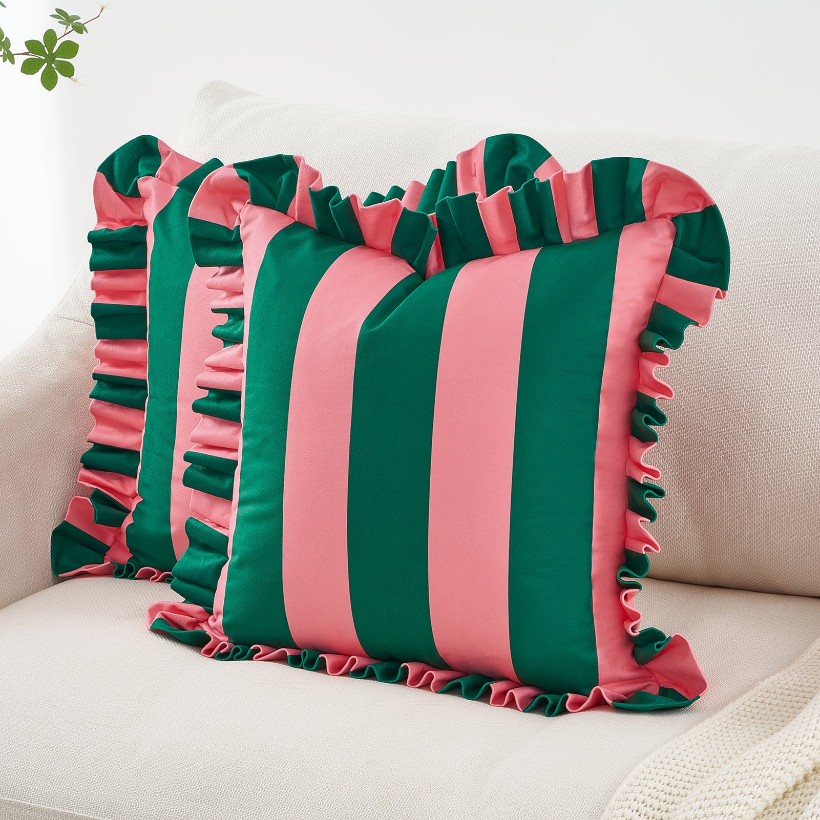 Striped pink and green pillow with ruffled edges on a white couch.
