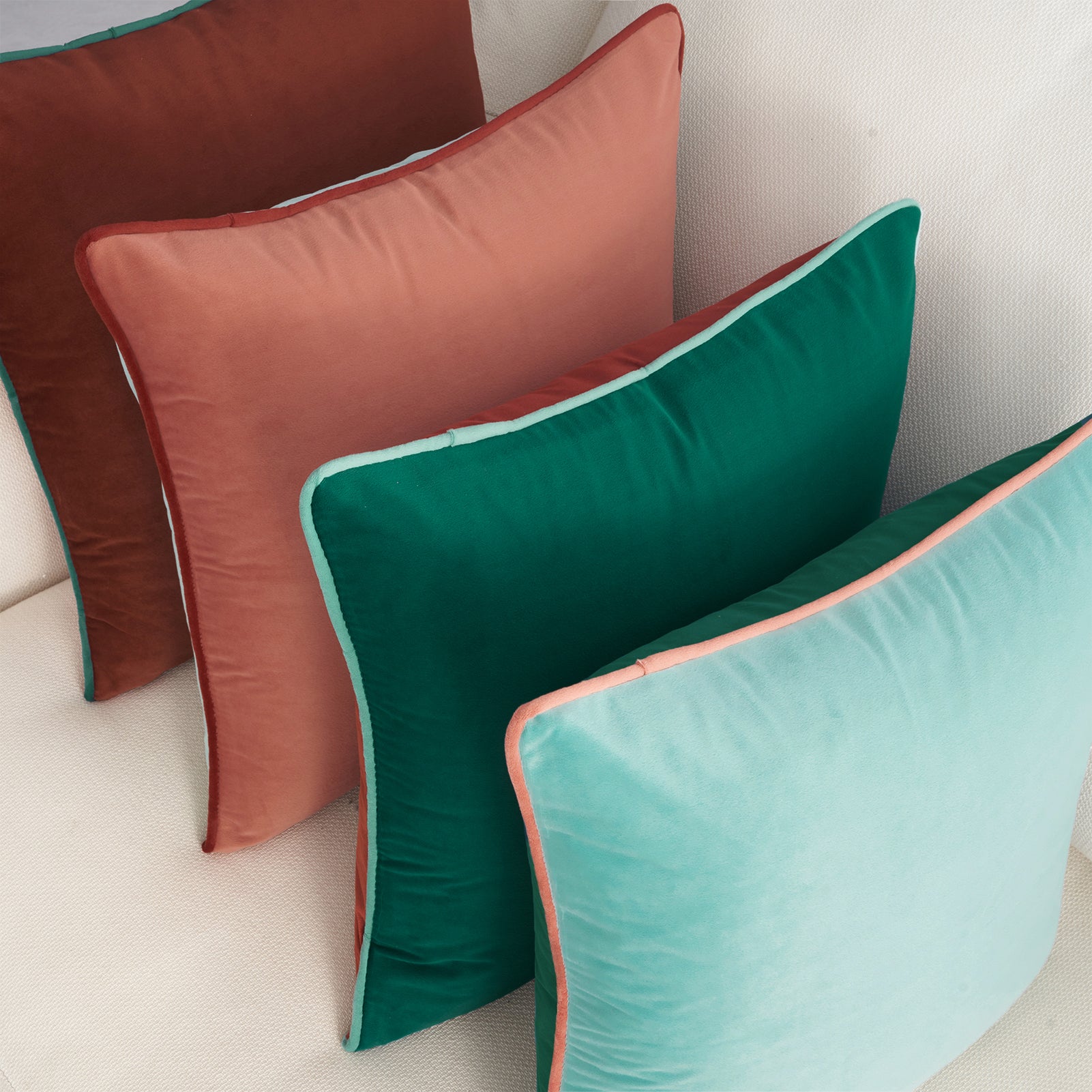Three colorful pillows on a light-colored sofa.
