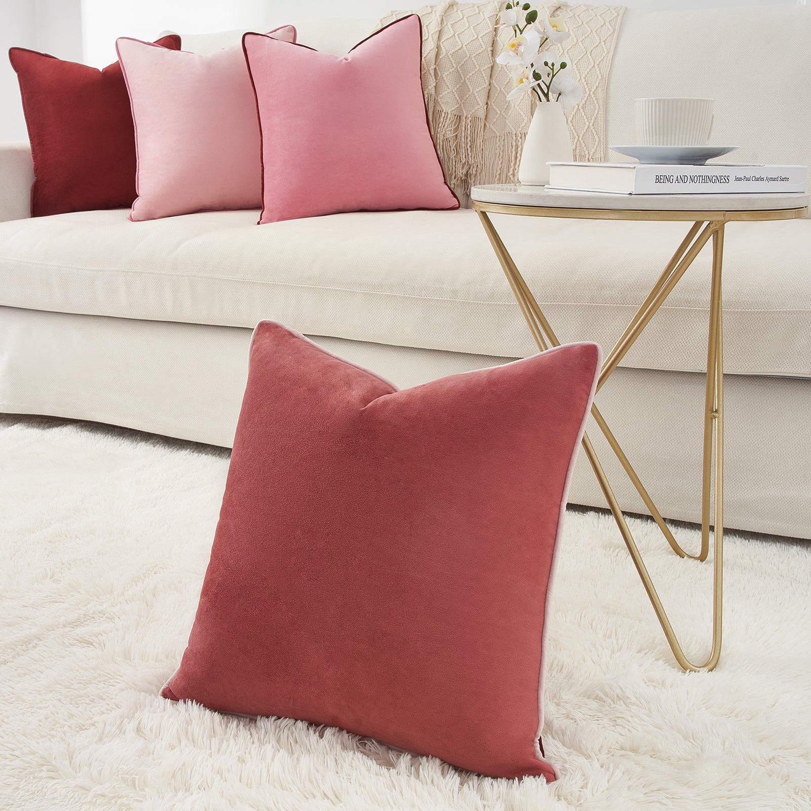 Red pillow on a white rug with a beige sofa and gold side table in the background