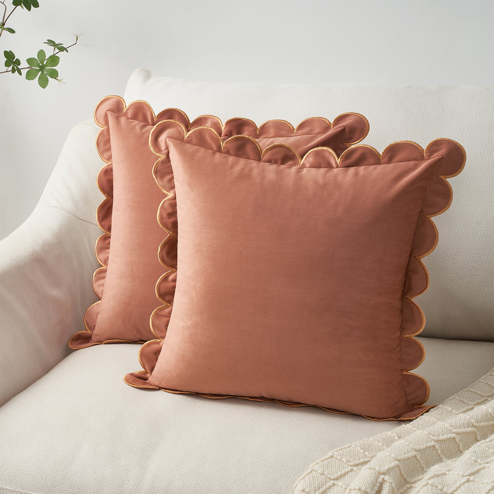 Pair of terracotta-colored cushions with scalloped edges on a light-colored sofa.
