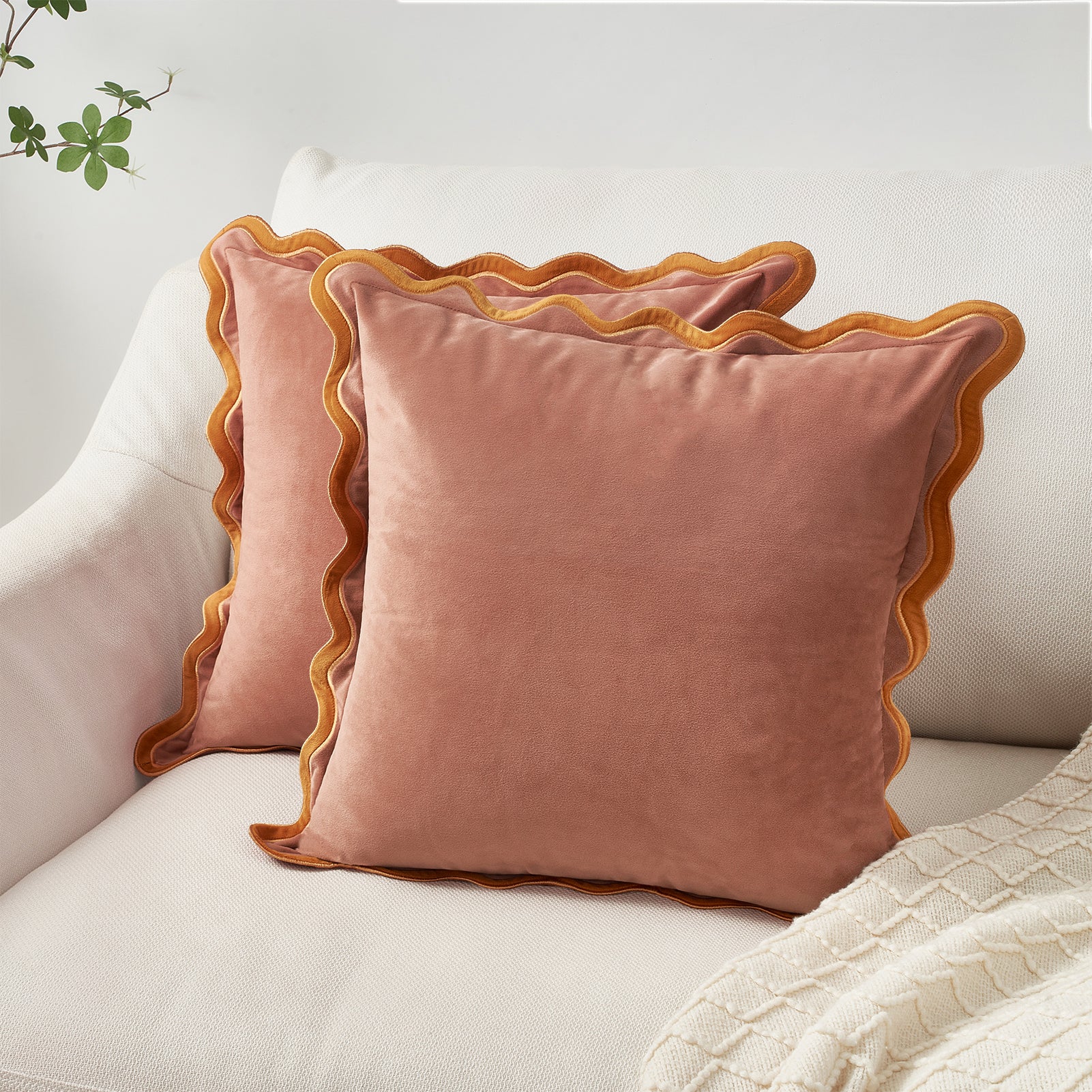 Pink velvet pillows with scalloped edges on a light-colored sofa.