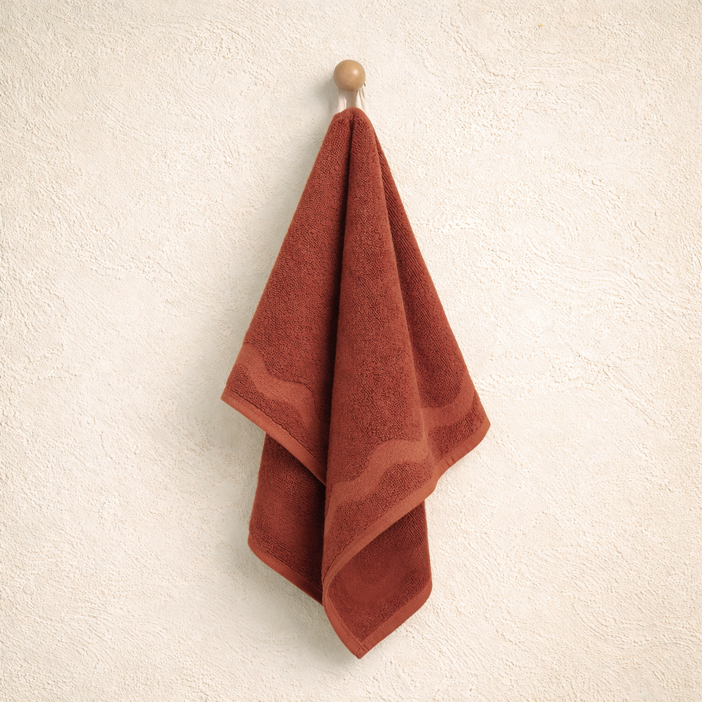 Red towel hanging on a wooden hook against a beige wall