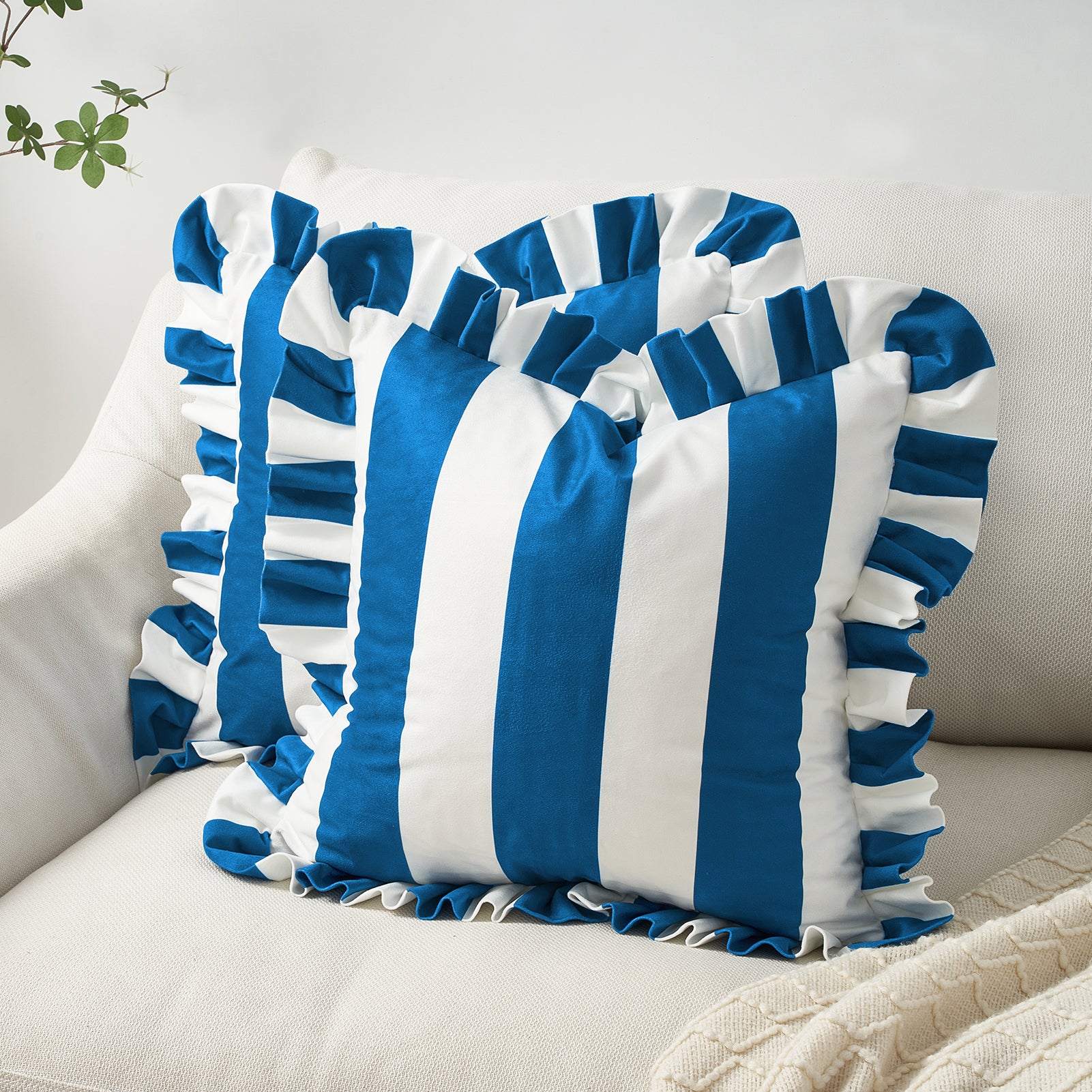 Blue and white striped pillows with ruffles on a beige couch.