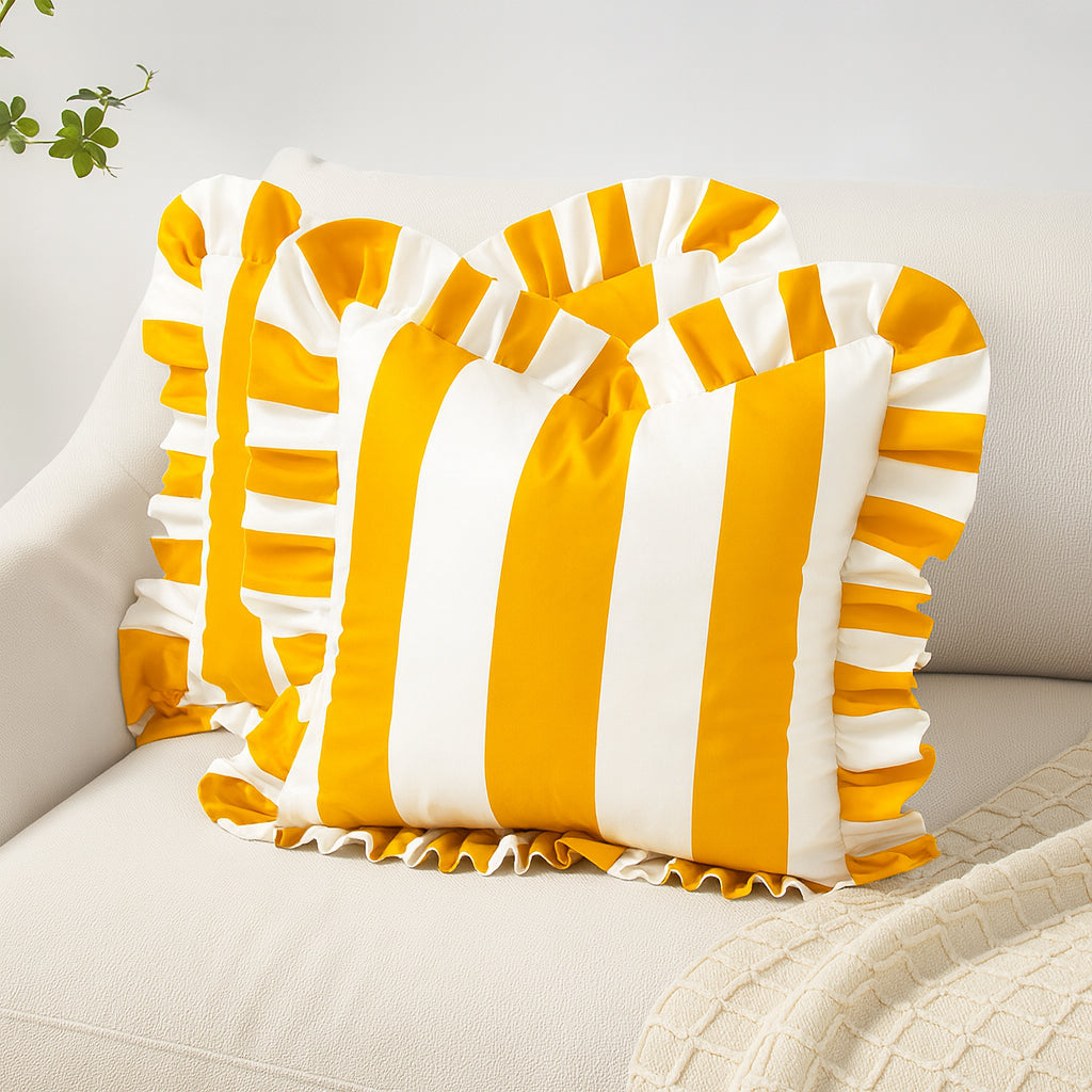Yellow and white striped pillow with ruffled edges on a light-colored couch.