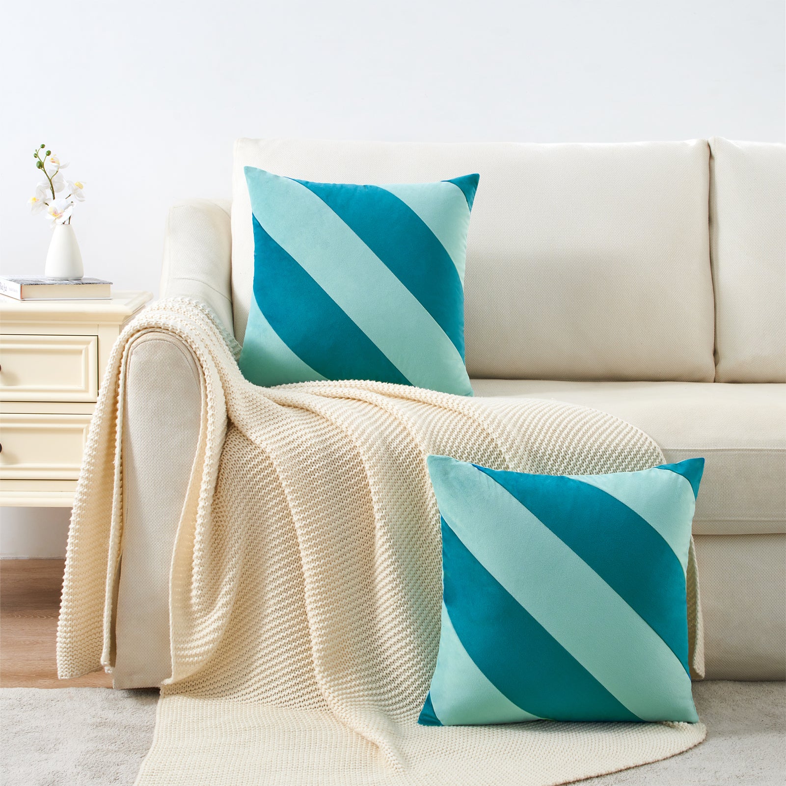 Teal and beige striped pillows on a beige sofa with a white wall background