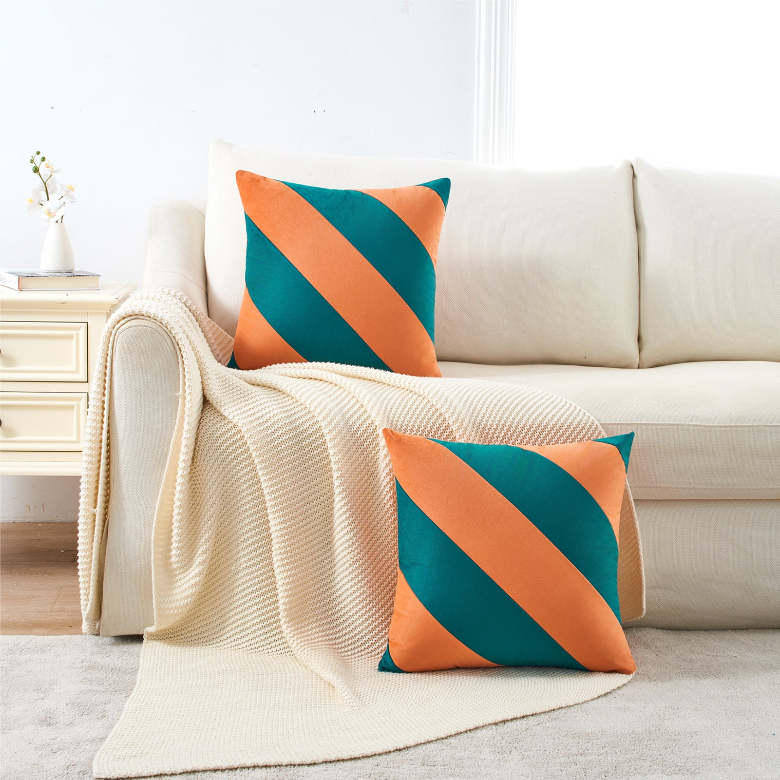 Decorative pillows with orange and teal stripes on a beige sofa in a living room.
