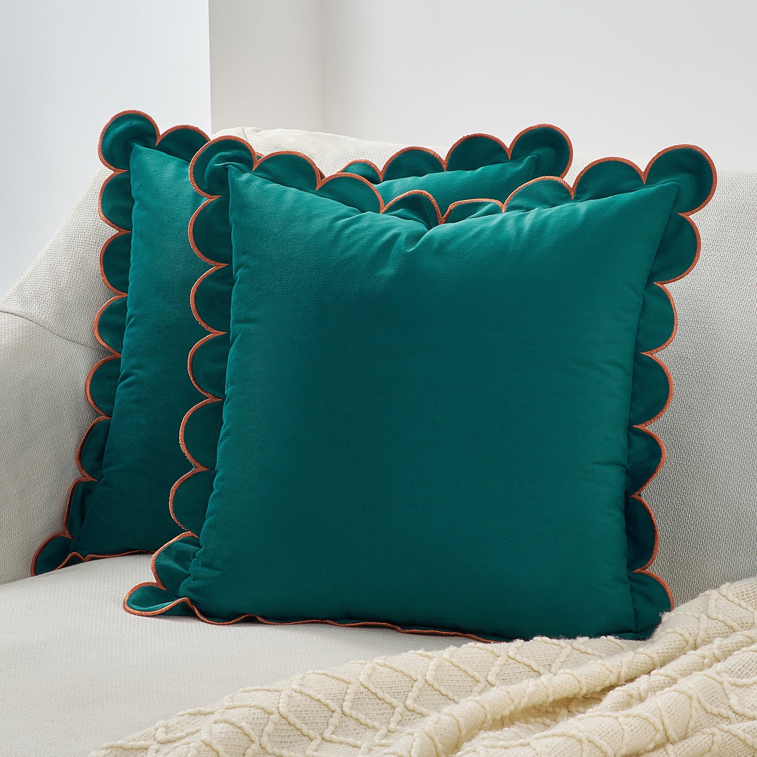 Teal pillows with scalloped edges on a white couch