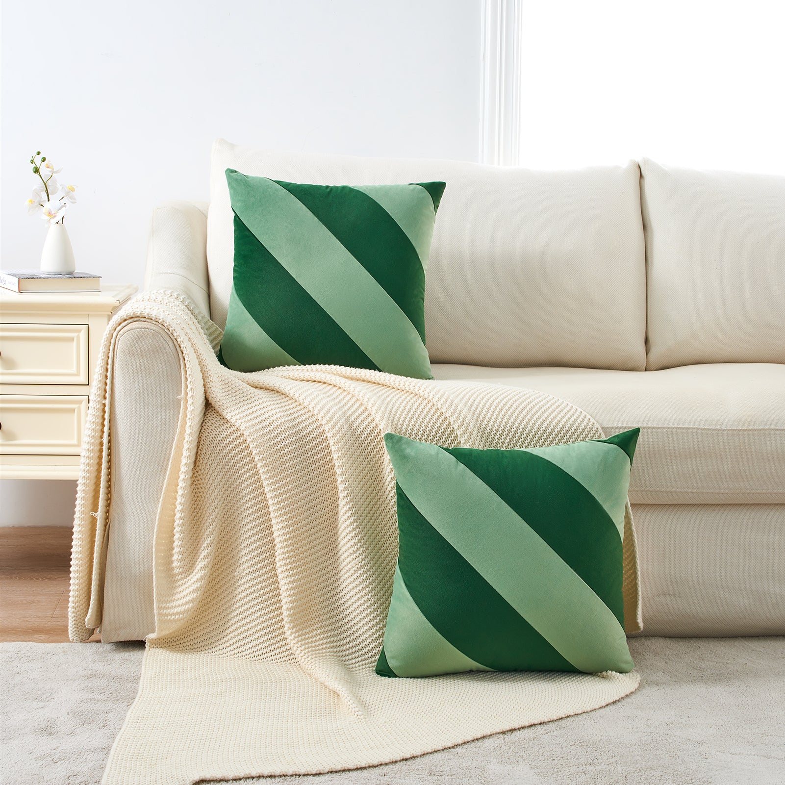 Green striped pillows on a beige sofa with a white wall background