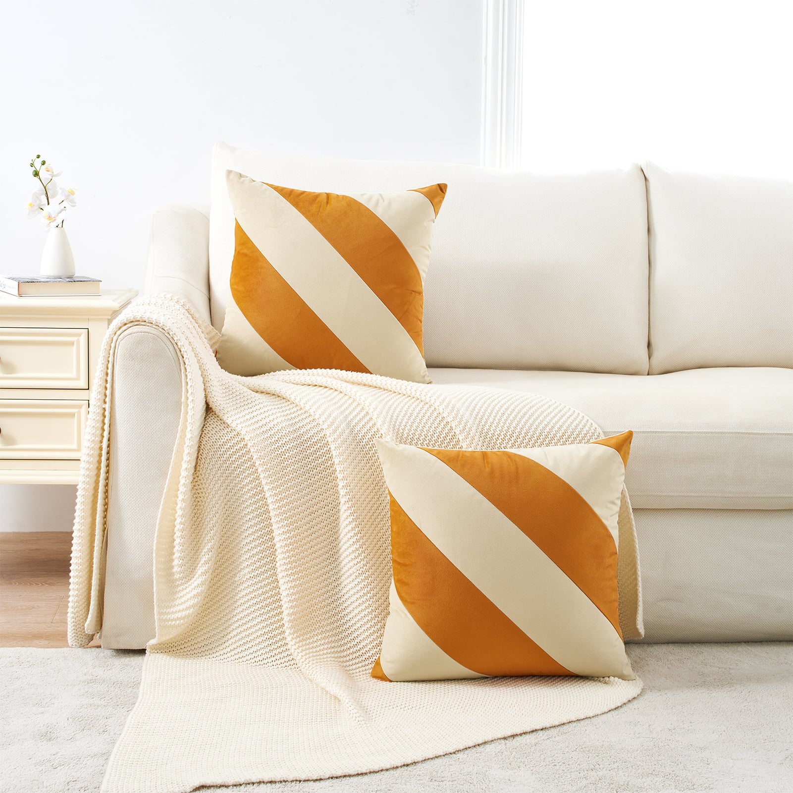 White sofa with orange and white striped cushions in a living room setting.