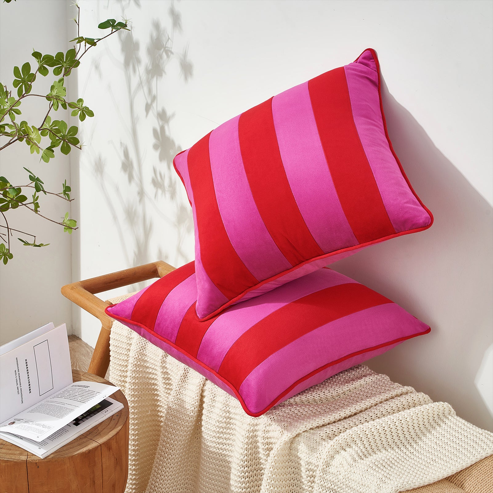 Red and pink striped cushions on a chair with a plant and book in the background