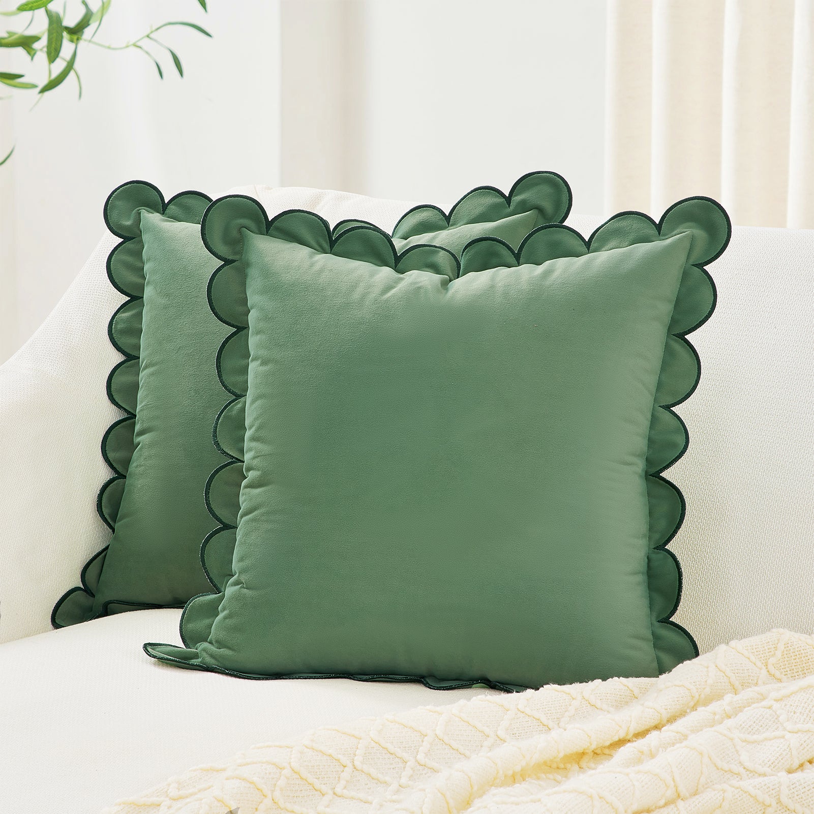 Green scalloped-edge pillow on a white couch with a light background