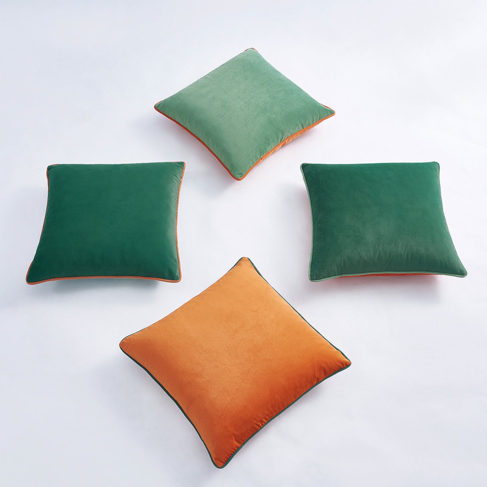 Four square pillows in green and orange on a white background