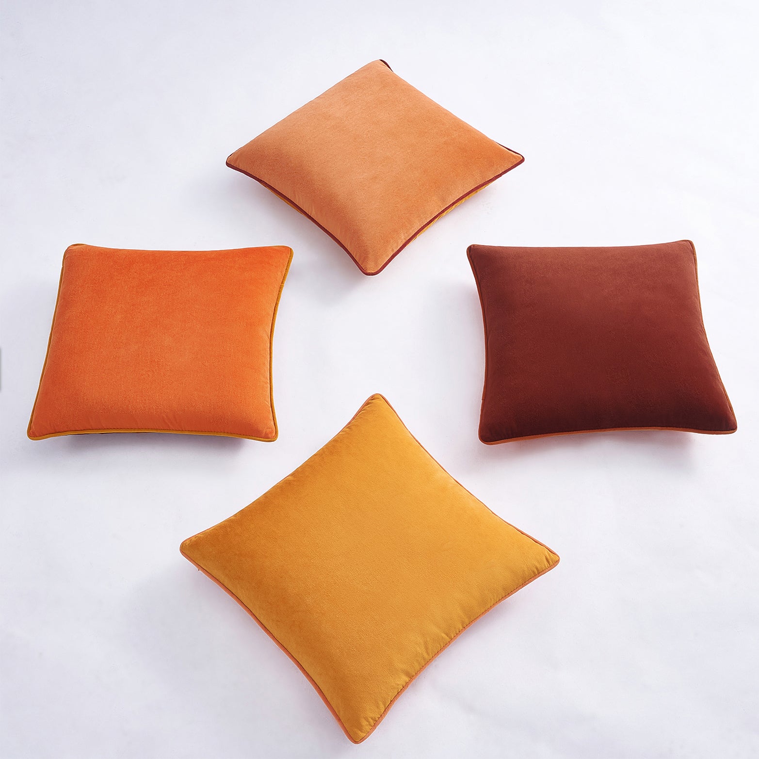 Four square pillows in orange and brown on a white background