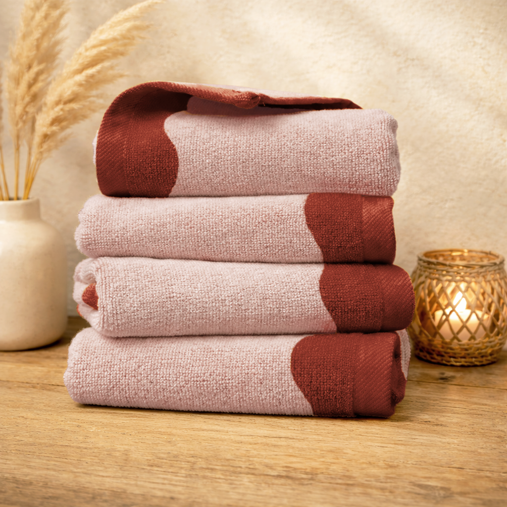 Stack of red and beige patterned towels on a wooden surface with decorative elements.