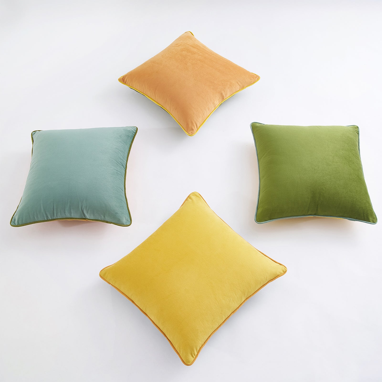 Four square pillows in green, yellow, and brown on a white background